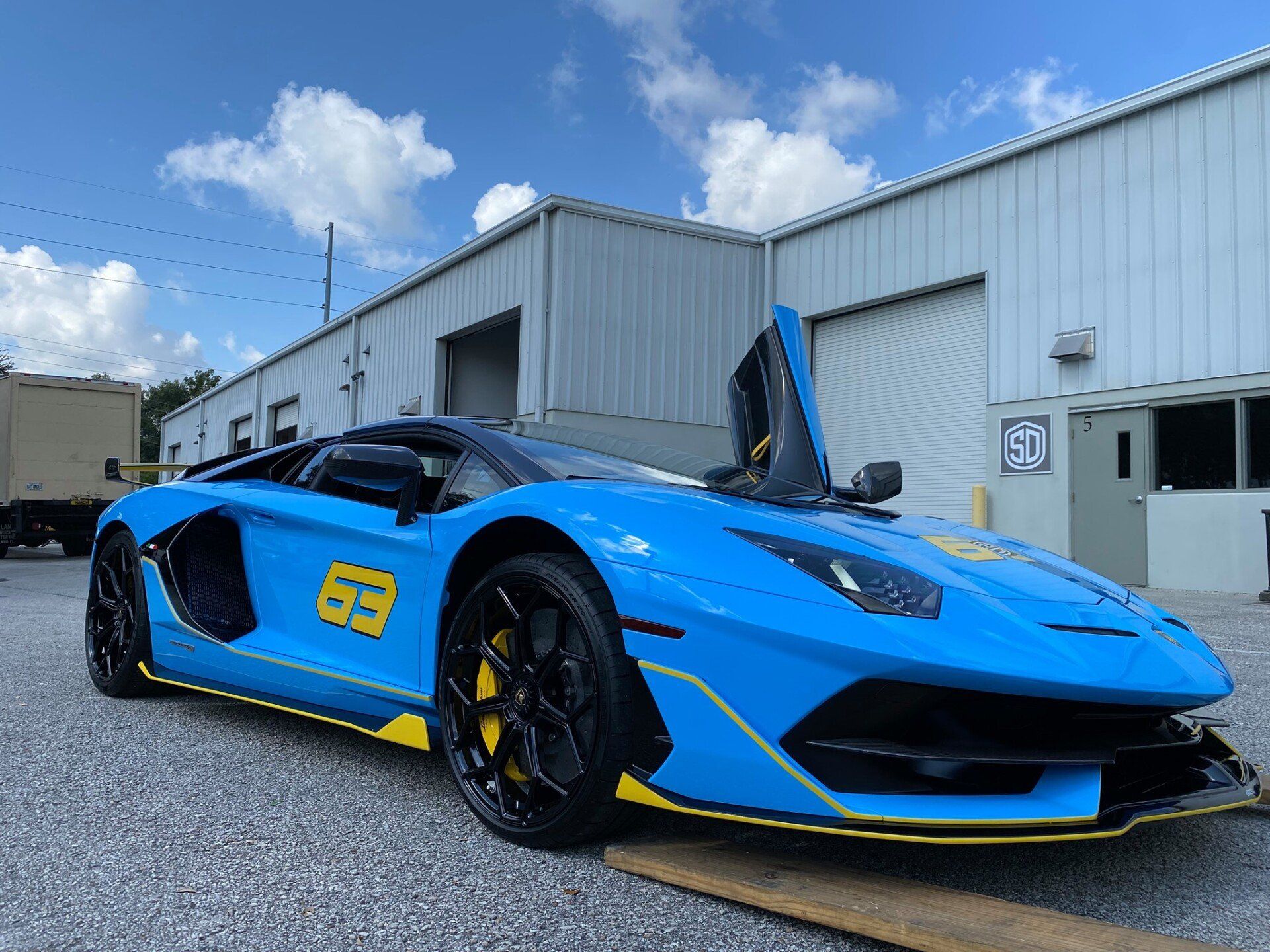 A blue lamborghini aventador is parked in front of a building.