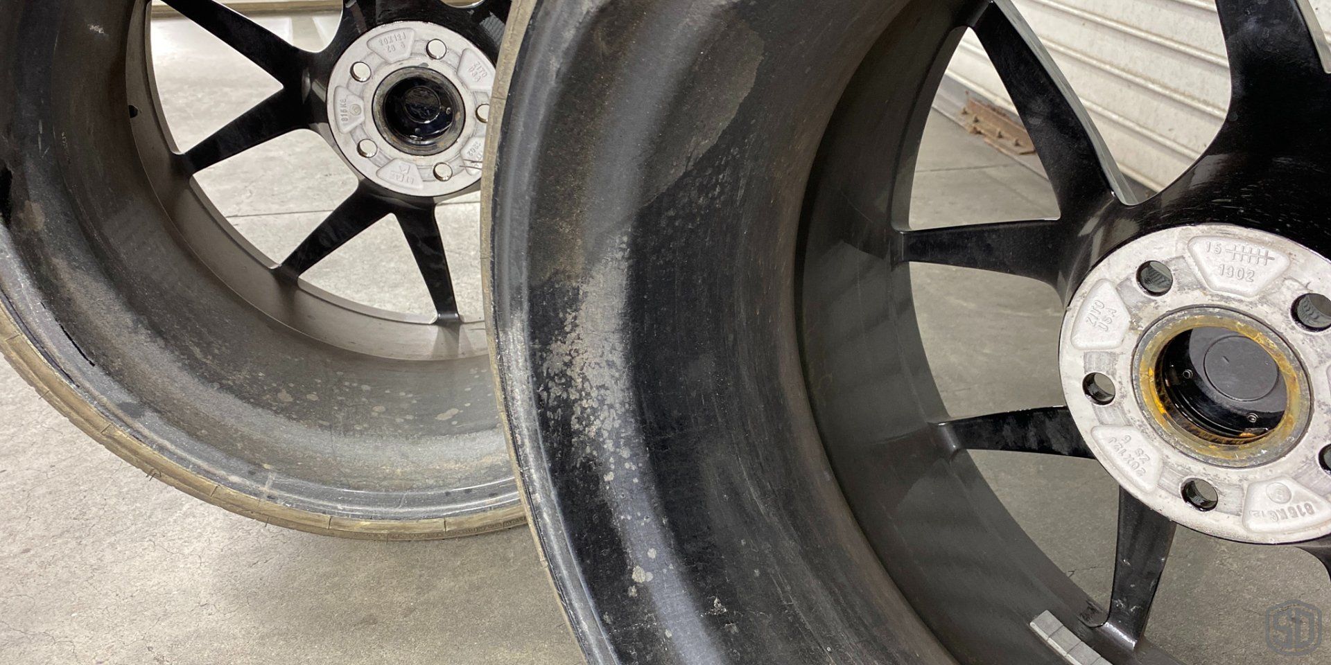 Two black wheels are sitting next to each other on the ground.