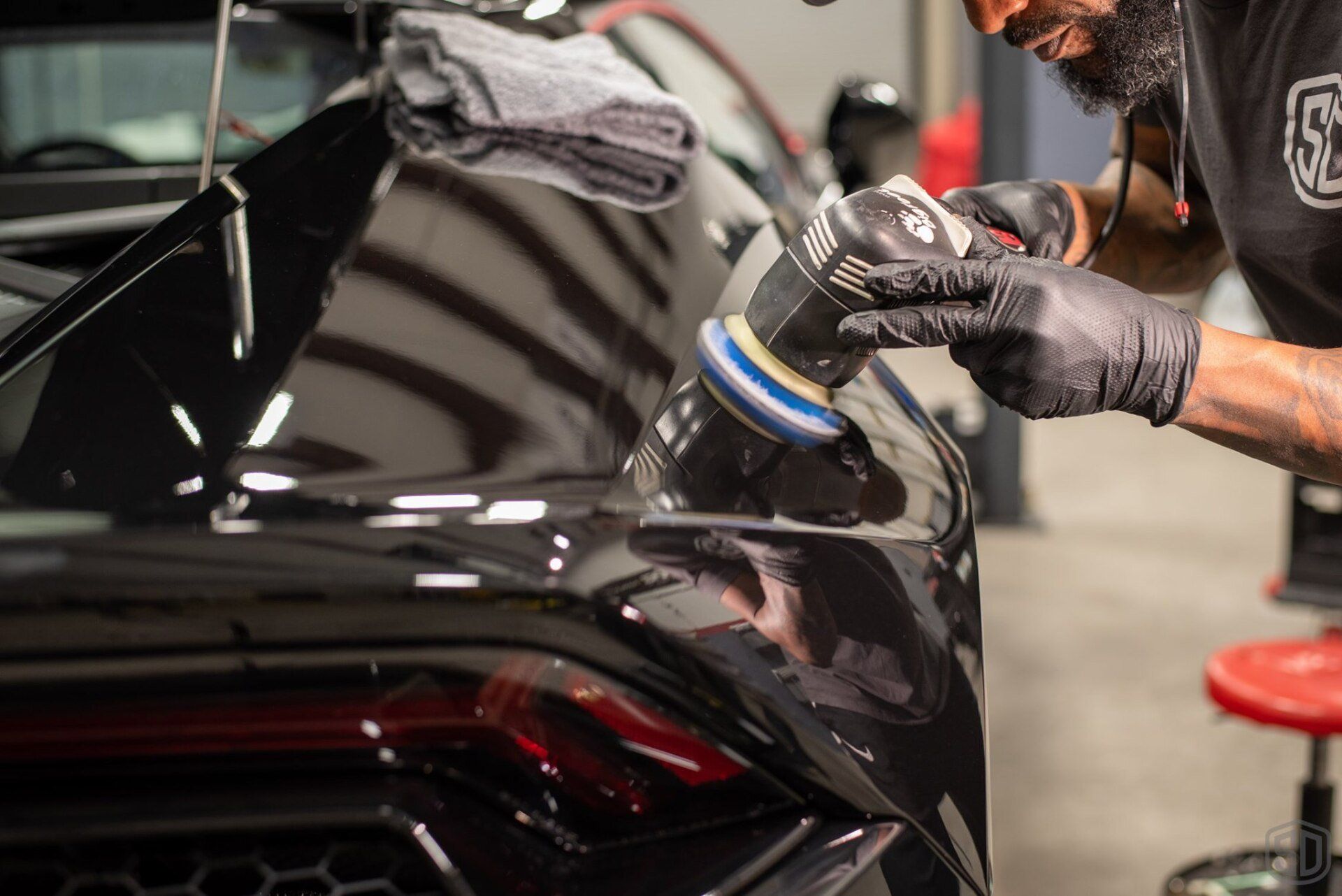 A man is polishing a black car with a machine.