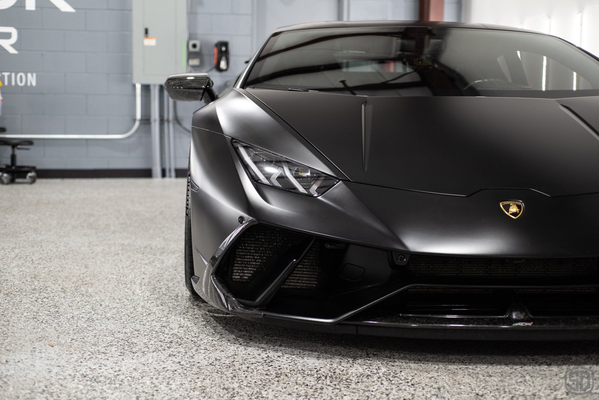 A black lamborghini huracan is parked in a garage.