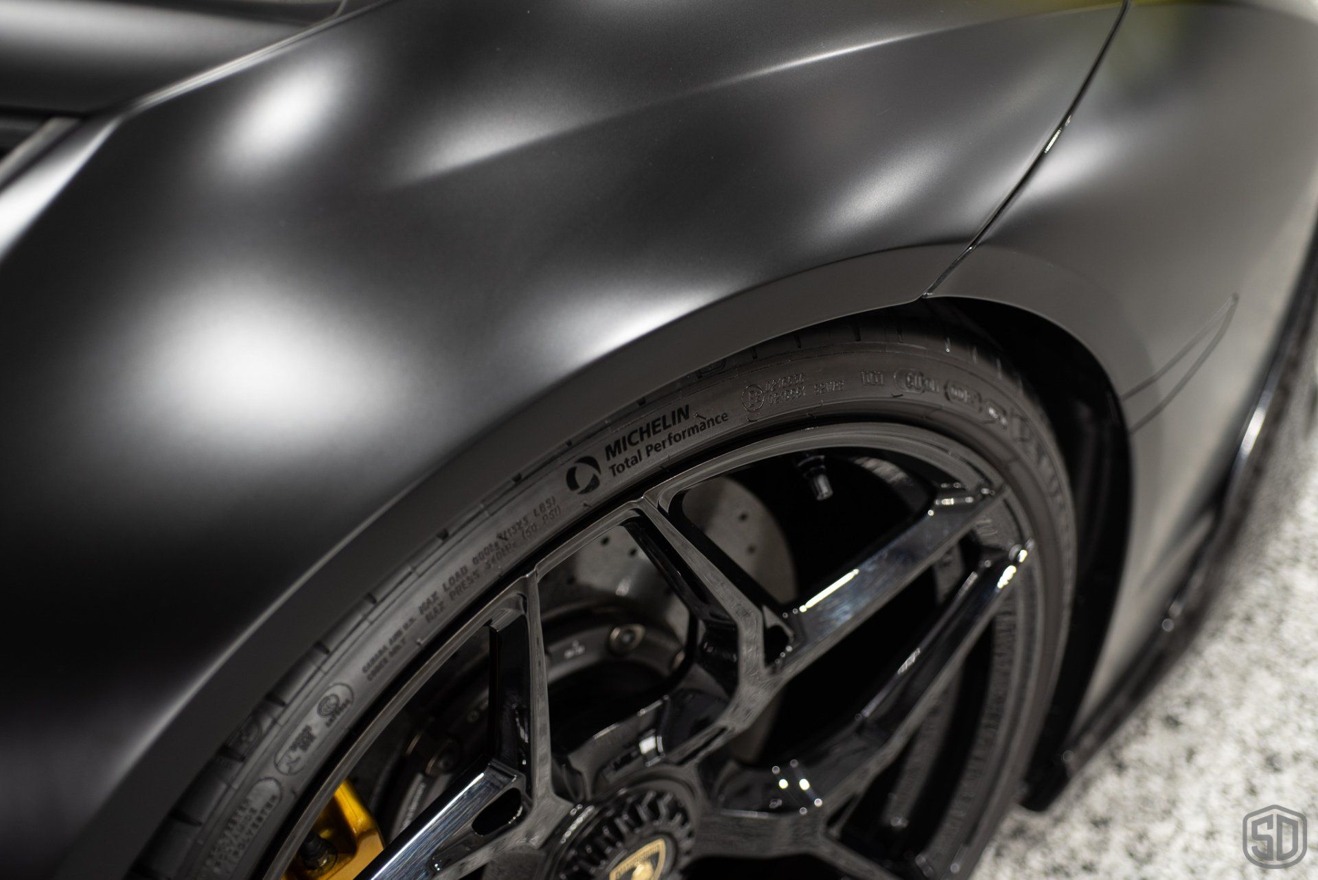 A close up of a black car 's fender and tire.