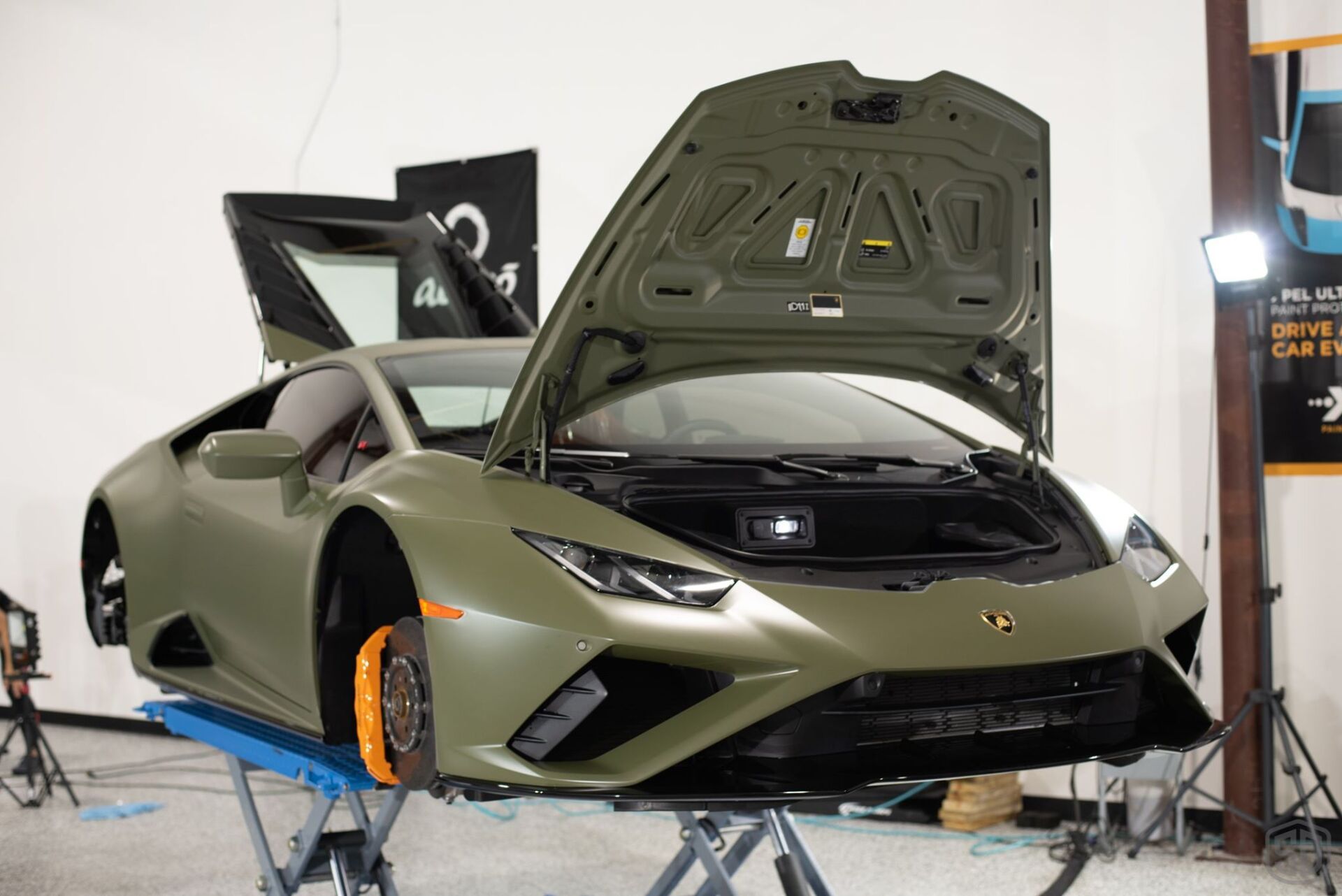 A green lamborghini huracan is sitting on a lift with its hood open.