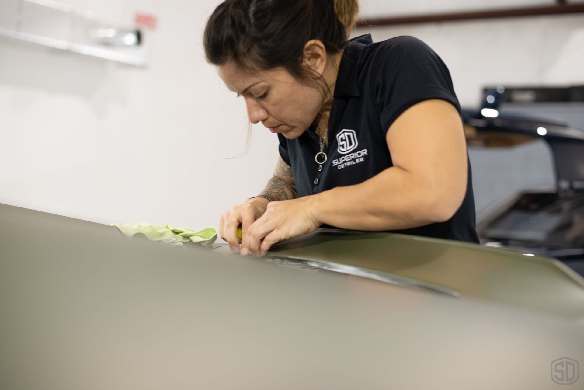 A woman is working on the hood of a car.