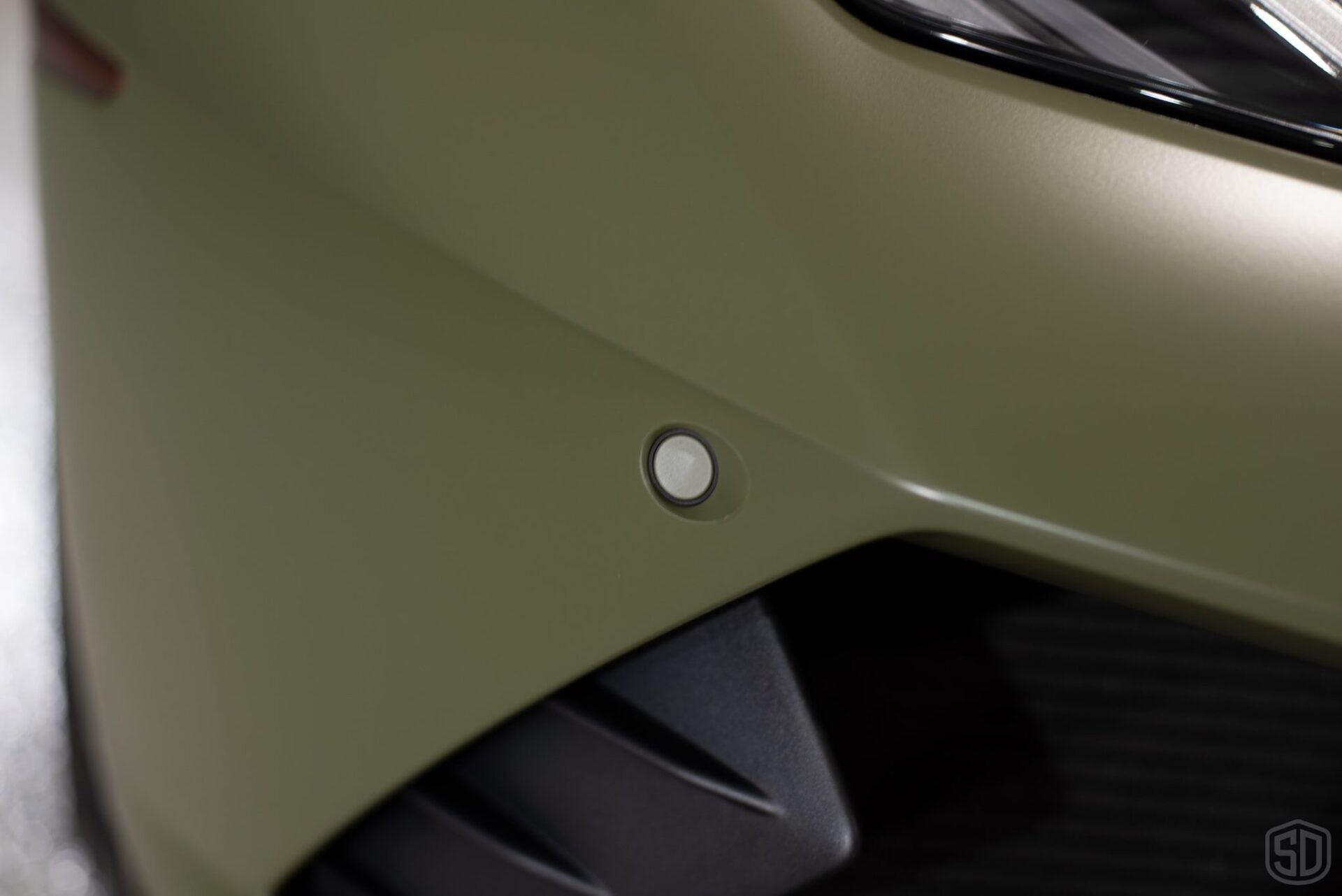 A close up of a car 's bumper with a white button on it.