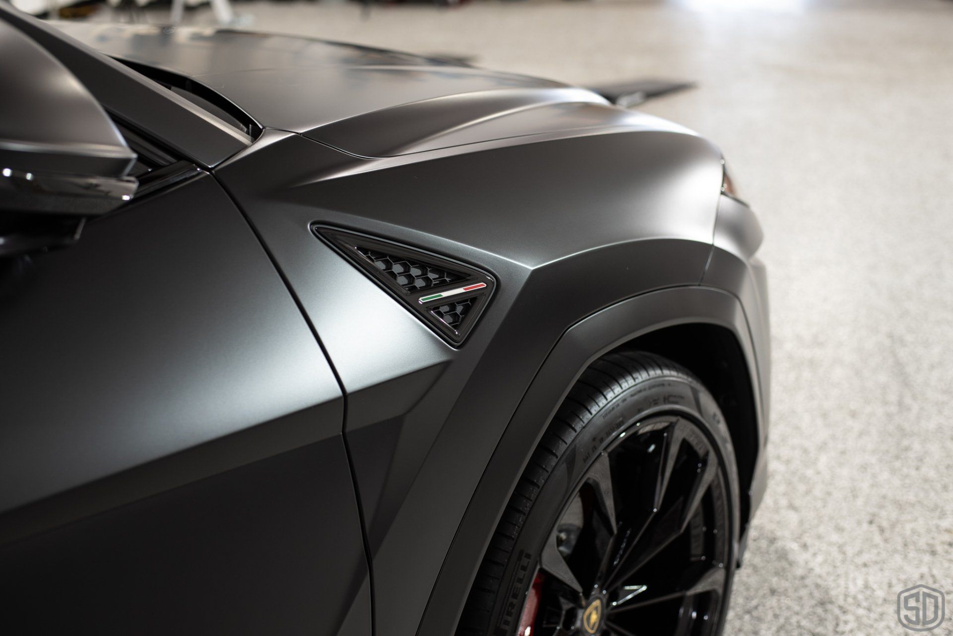 A close up of a black car 's fender and hood.