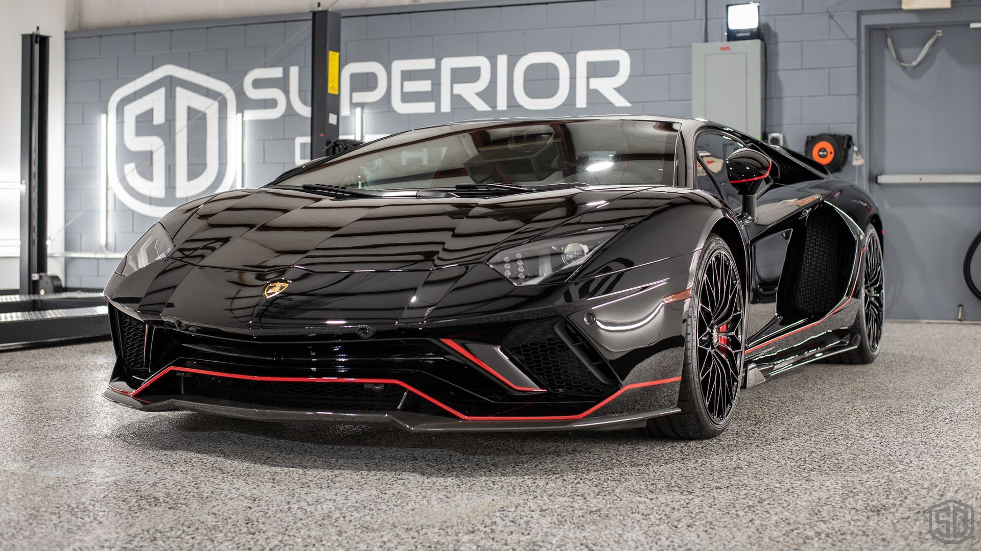 A black lamborghini aventador is parked in a garage.