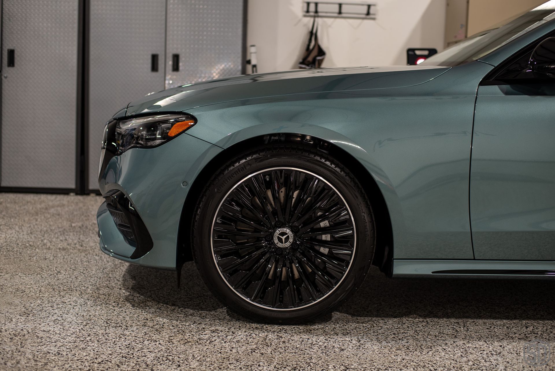 A blue car is parked in a garage with black wheels.