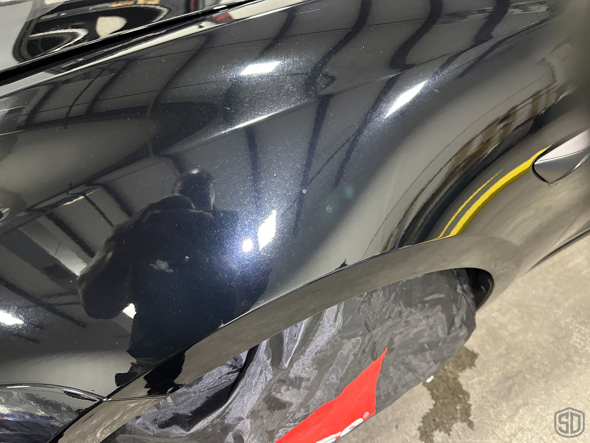 A close up of a black car with many scratches & imperfections