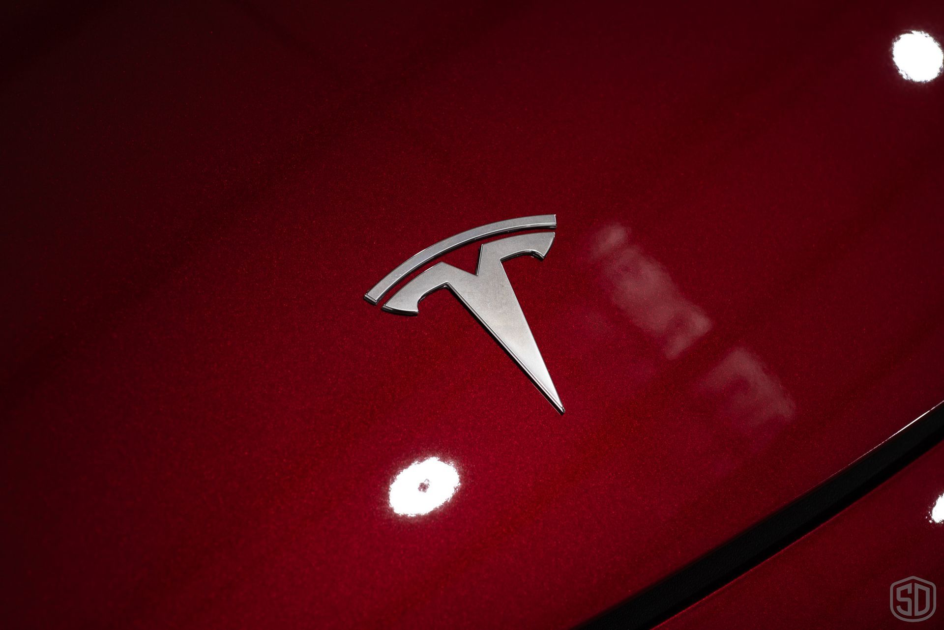 closeup of tesla logo on red tesla
