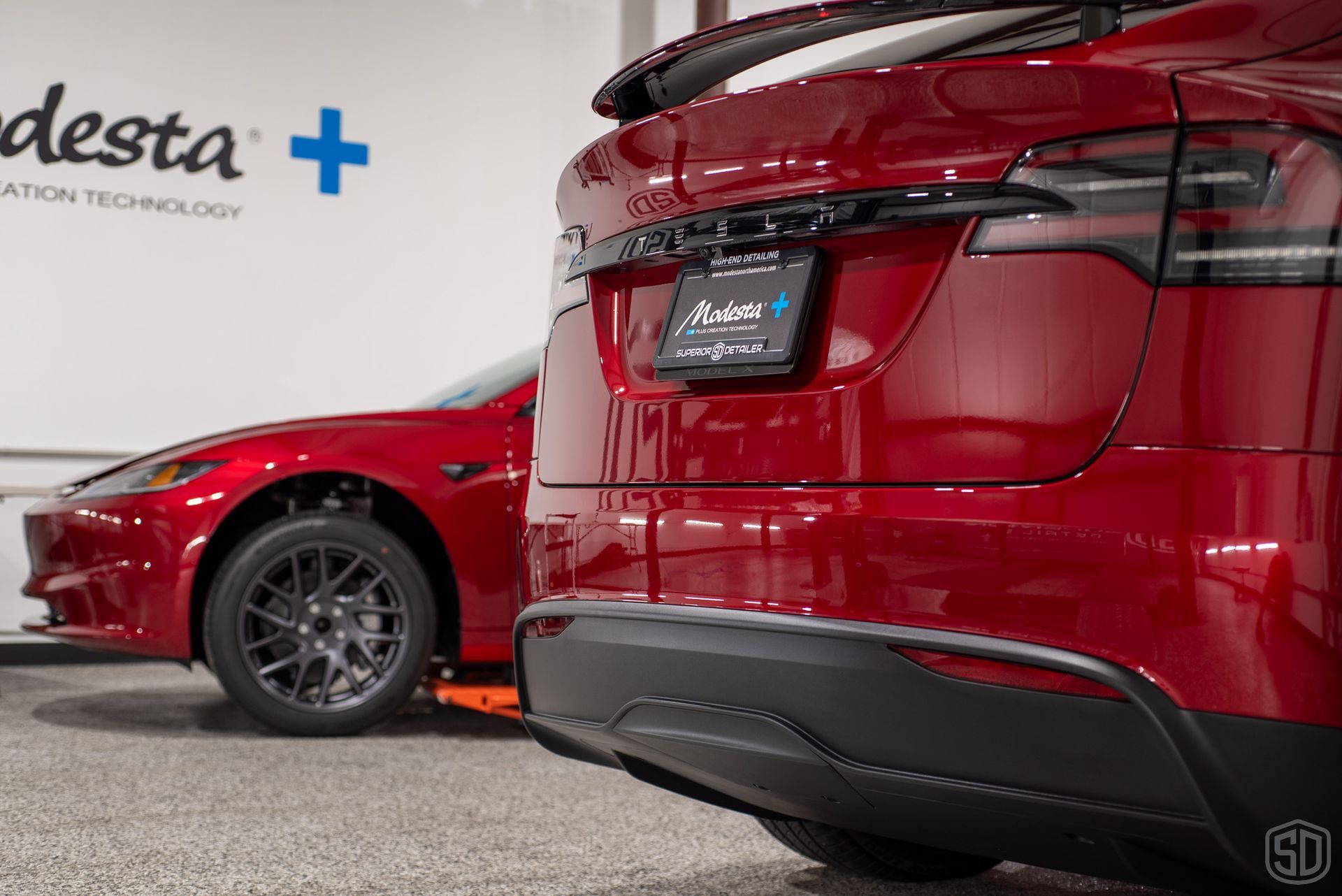 A red tesla model is parked in a garage.