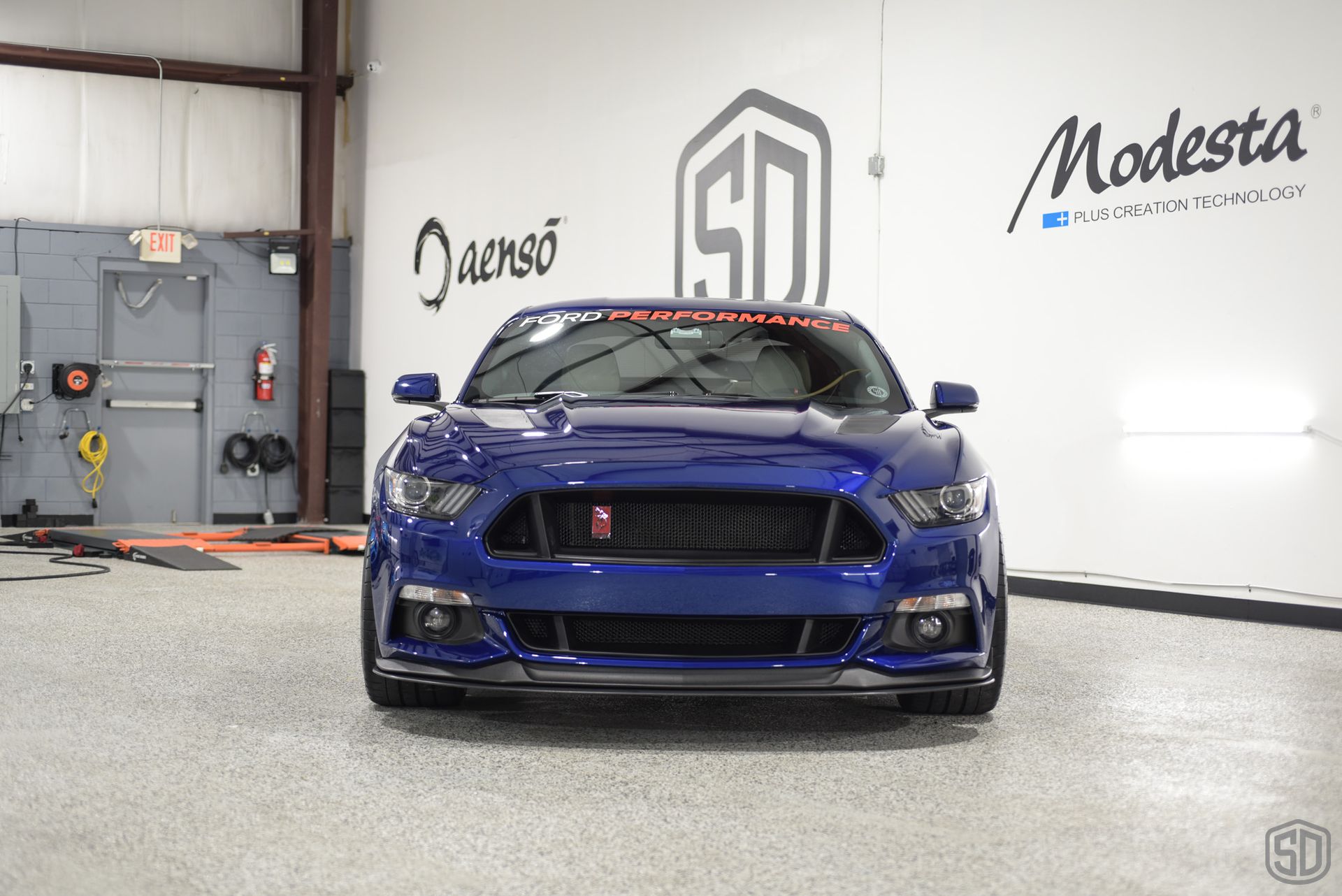 A blue ford mustang is parked in a garage.