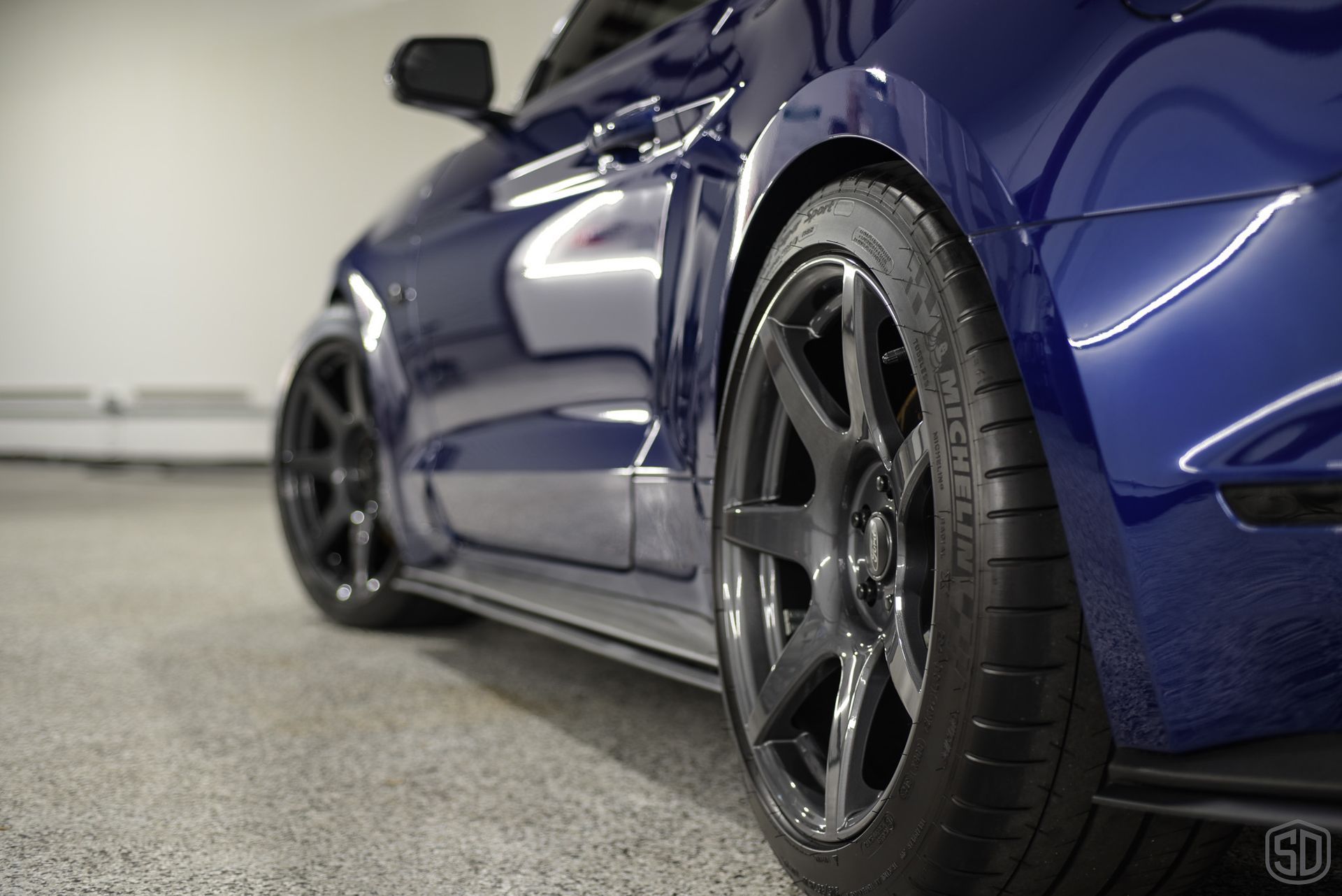 A blue ford mustang is parked in a garage.