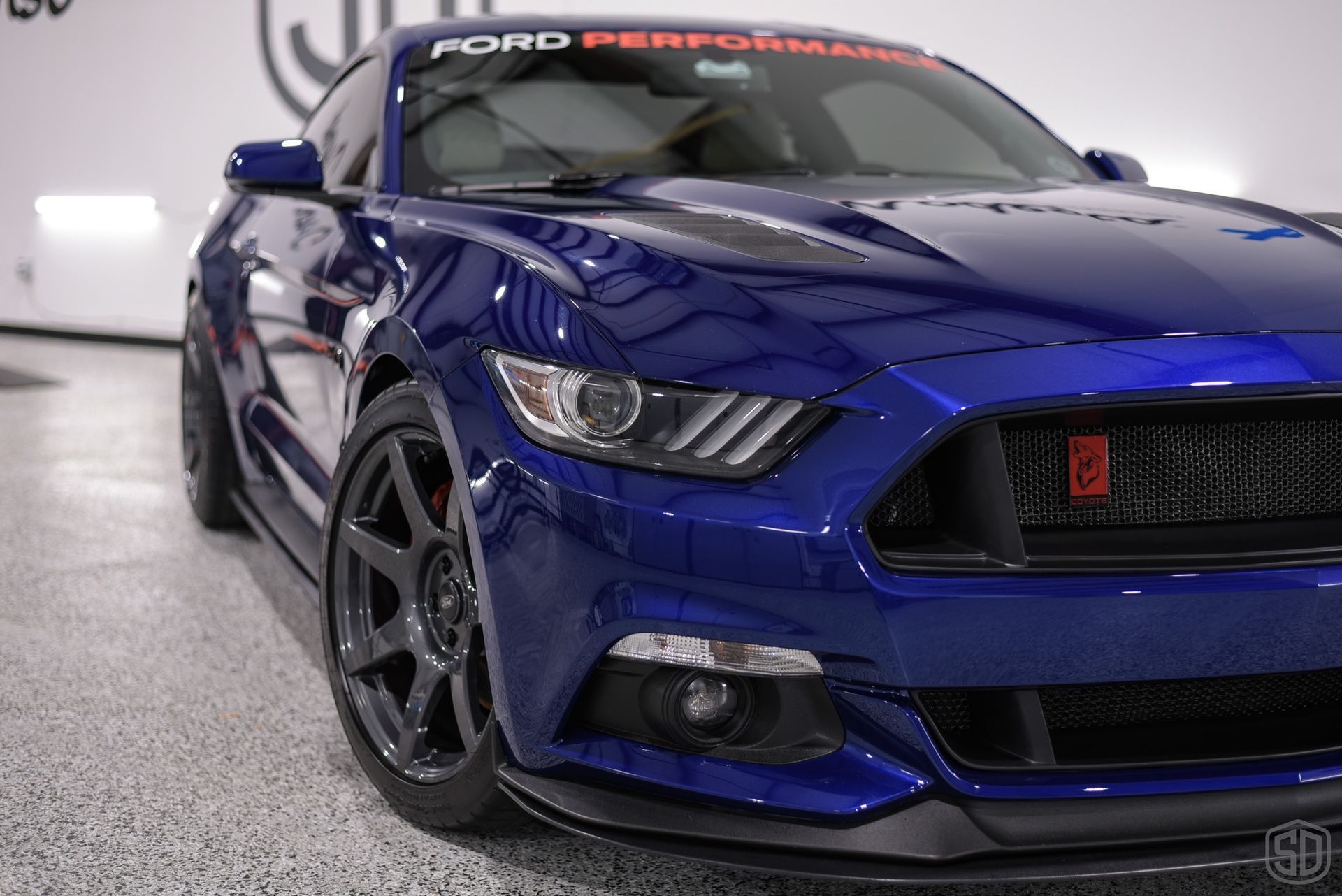 A blue ford mustang is parked in a garage.