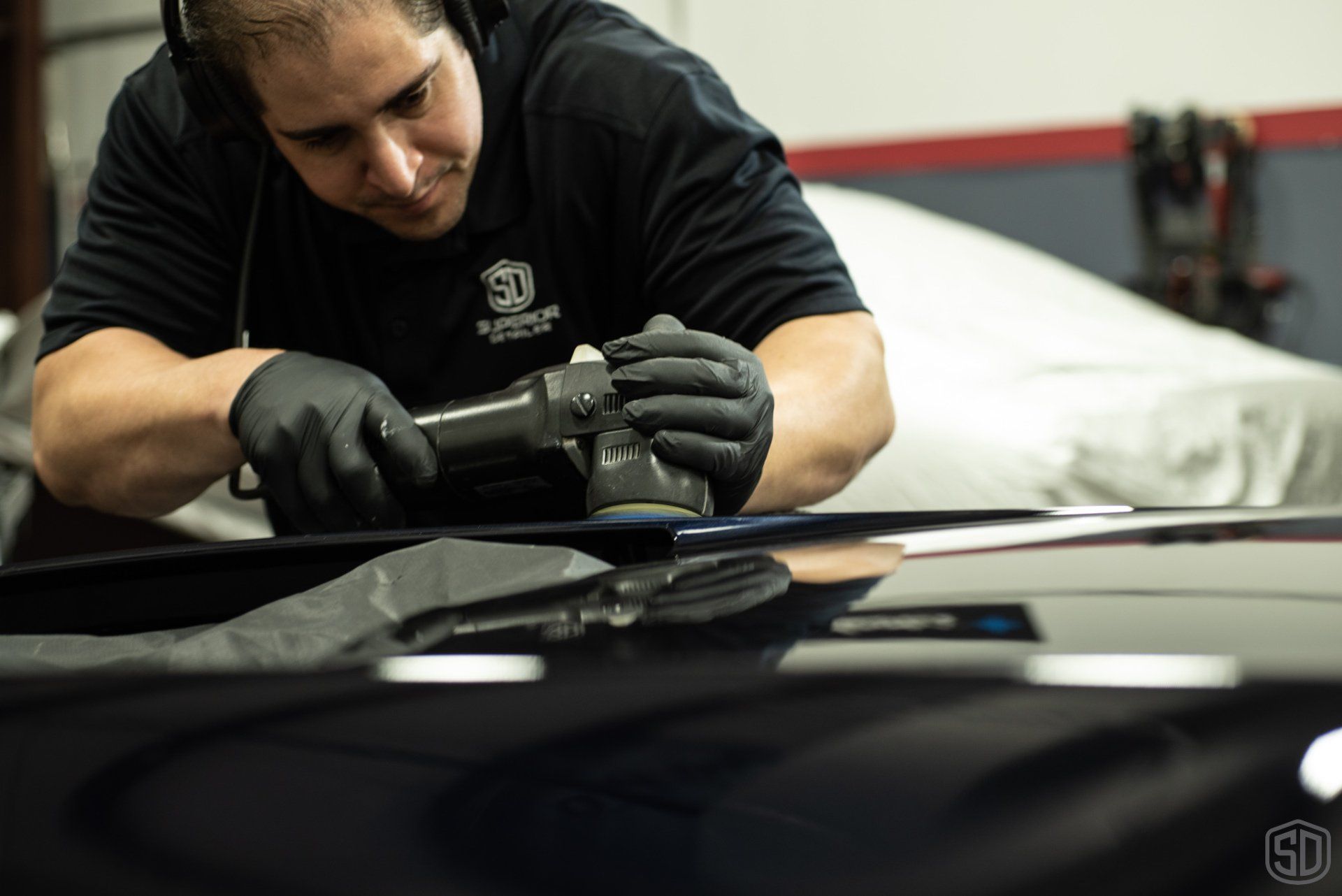 A man is polishing the hood of a car.