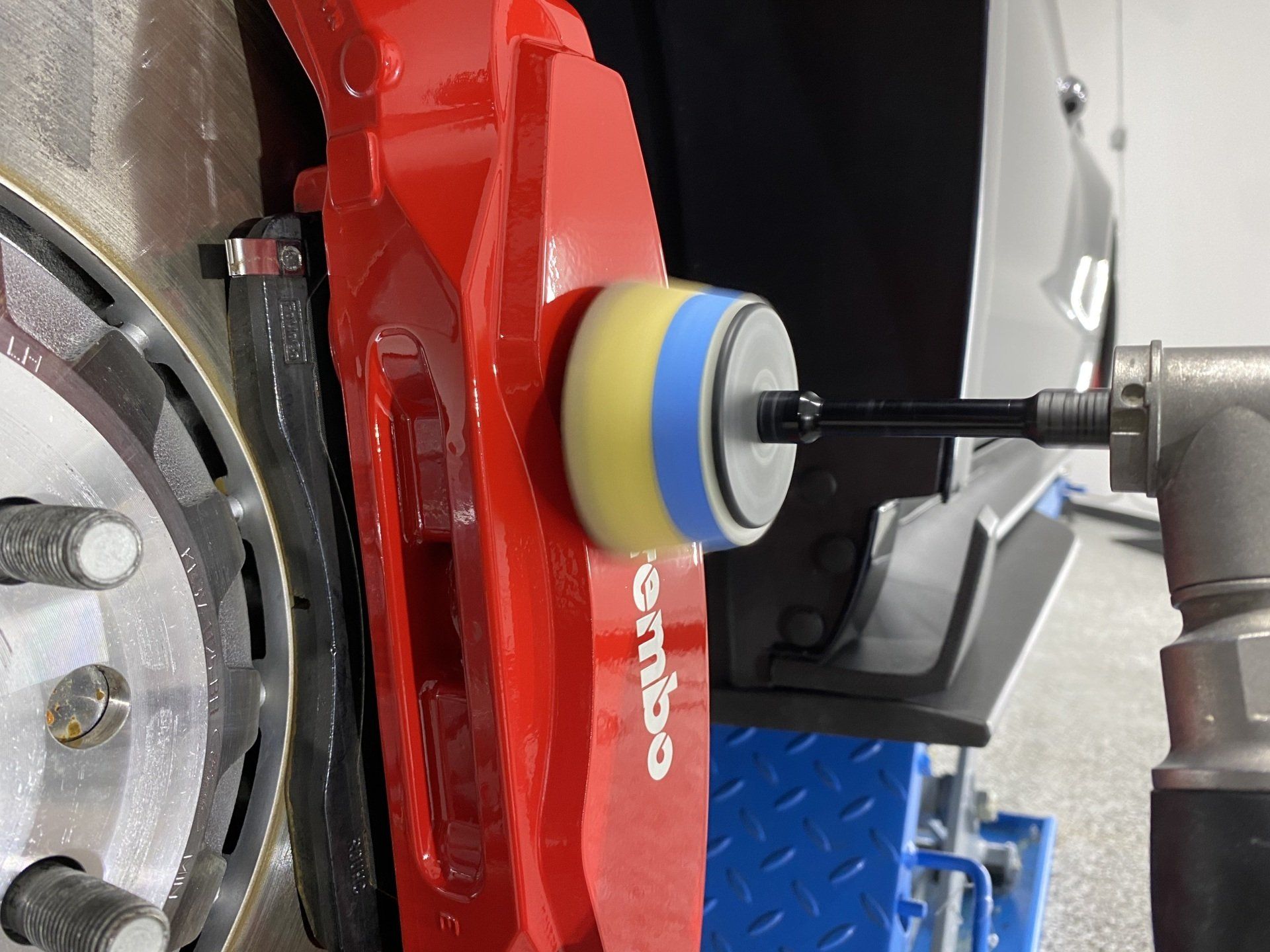 A red brembo brake is being polished with a sponge