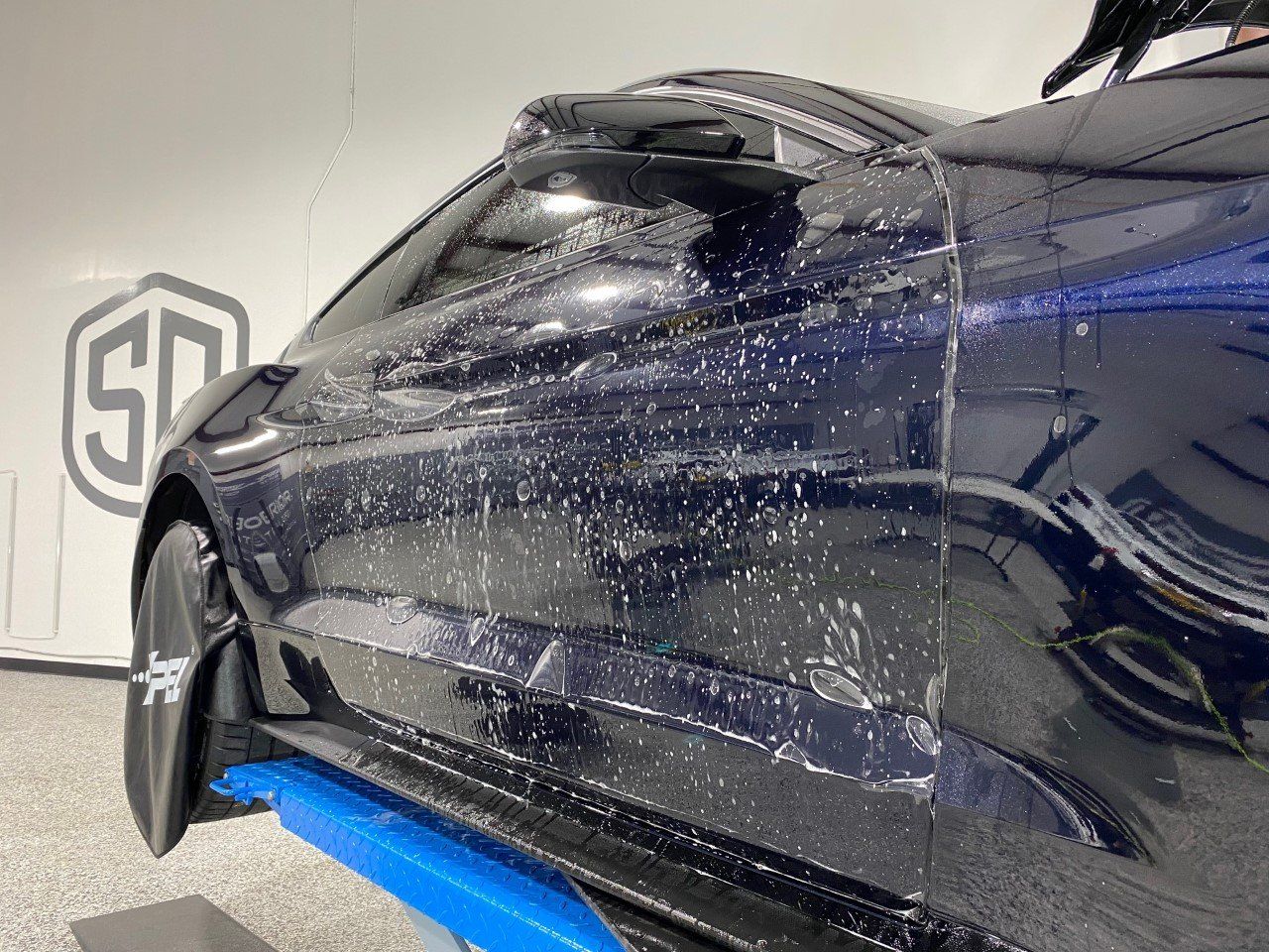 A black car is sitting on a lift in a garage.