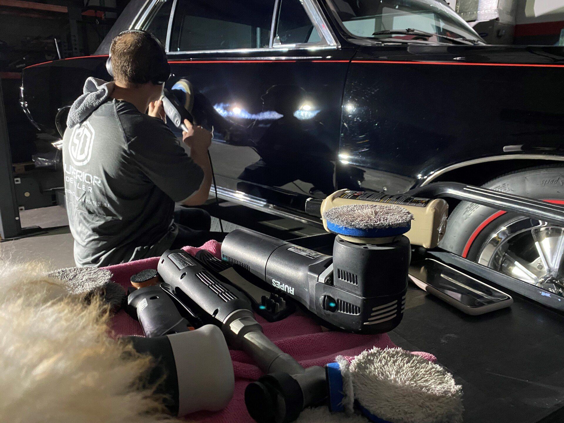 A man is polishing the side of a black car.