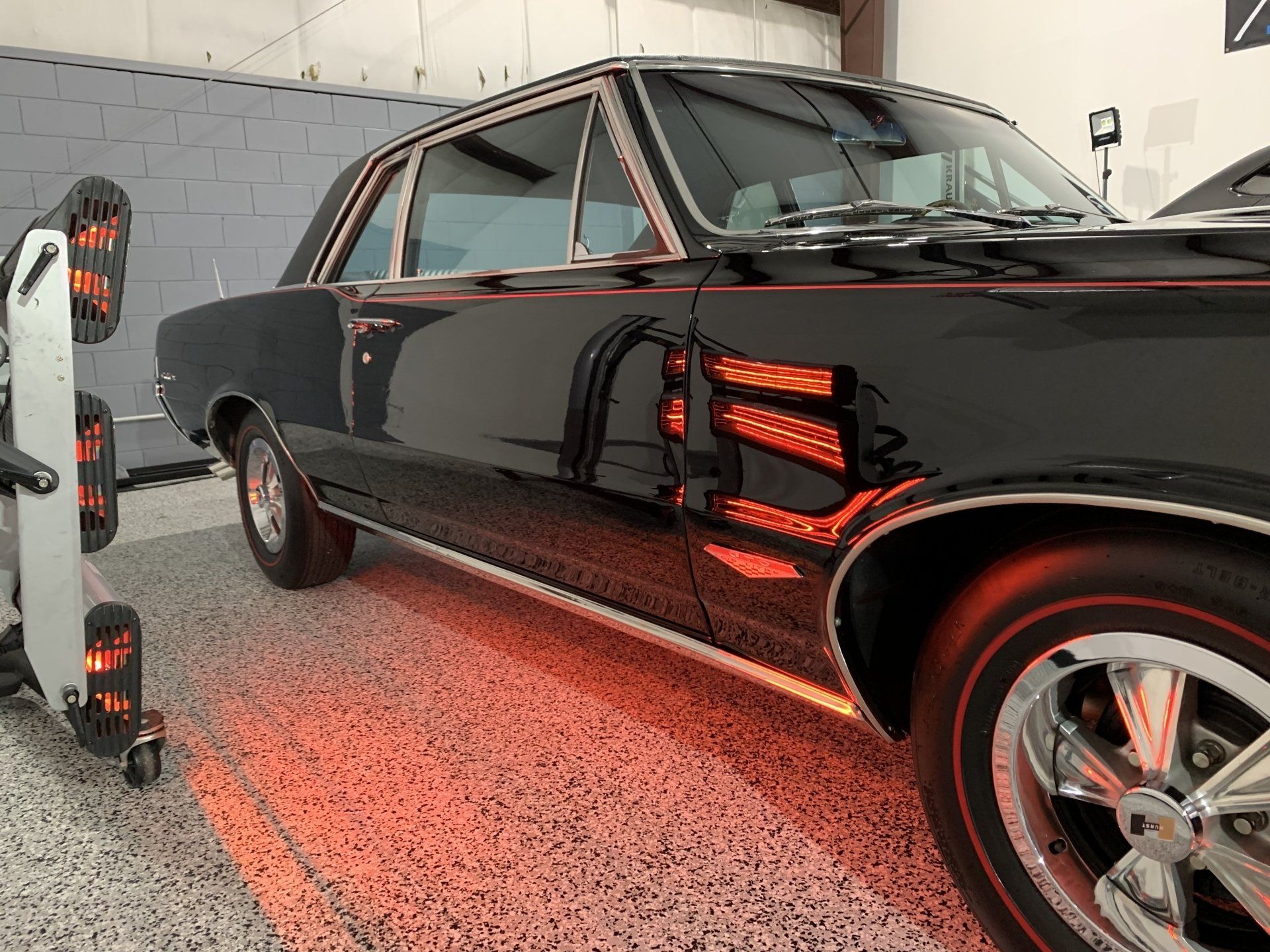 A black car is sitting in a garage next to a machine.