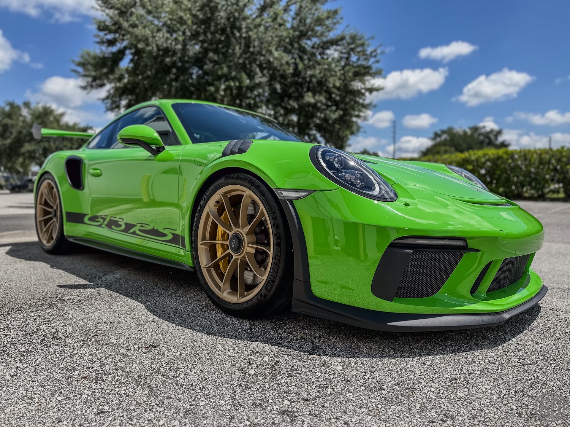 A green porsche 911 gt3 rs is parked in a parking lot.