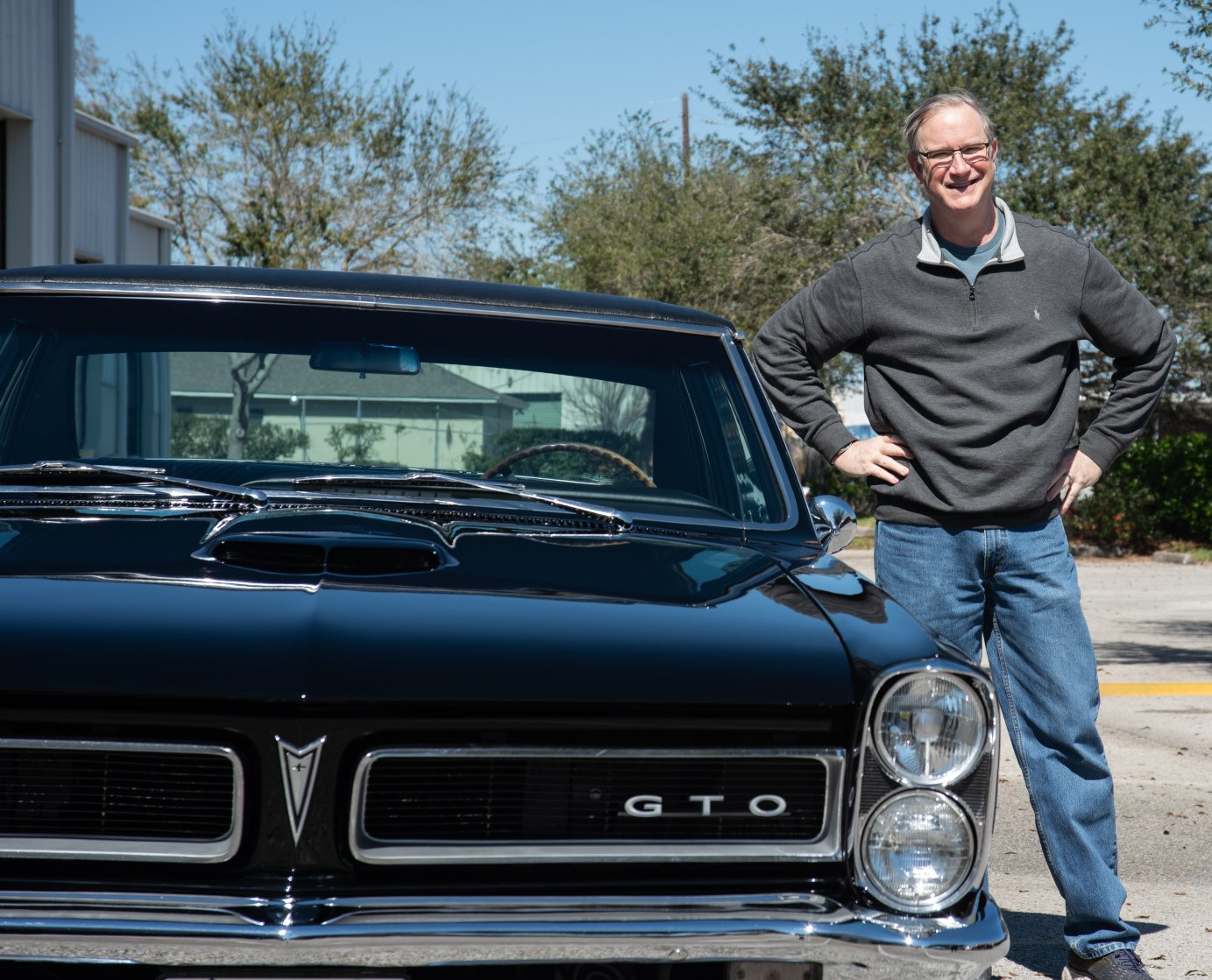 A man is standing in front of a black gto car