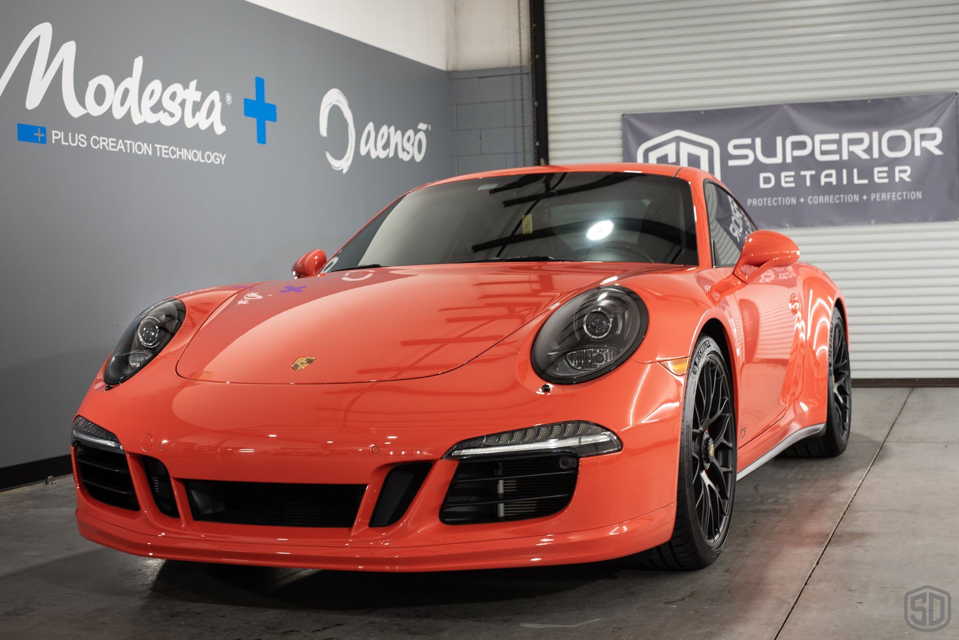 An orange porsche 911 gt3 is parked in a garage.