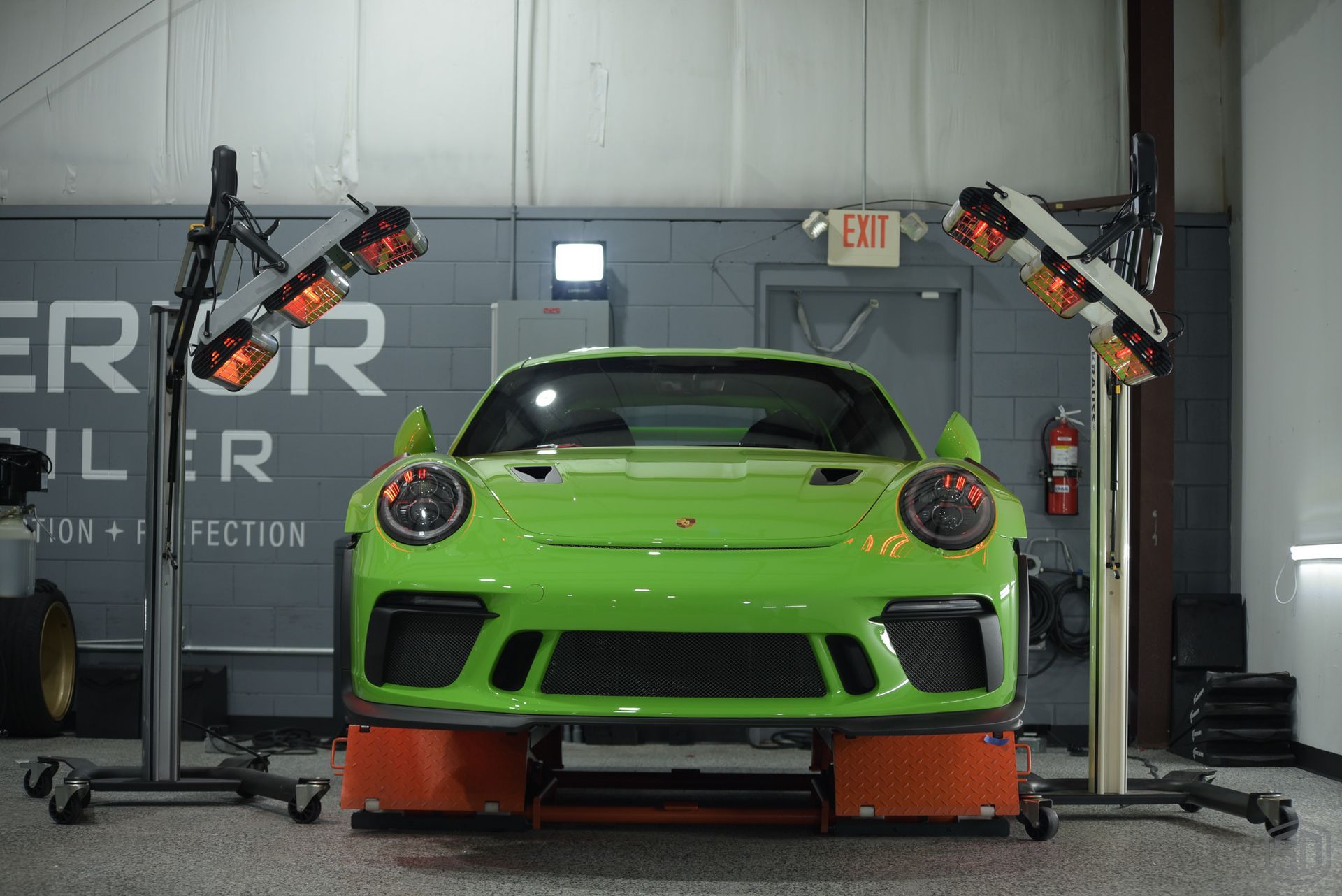 A green sports car is sitting on a lift in a garage.