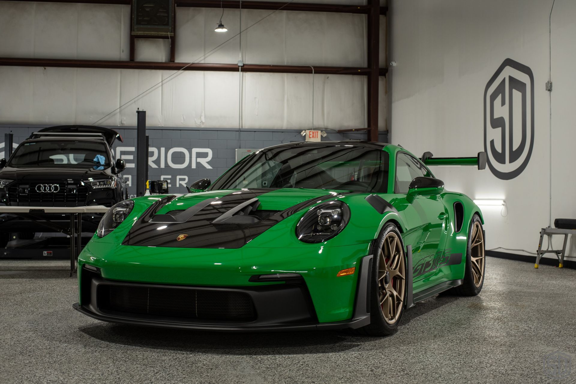 A green porsche 911 gt3 rs is parked in a garage.