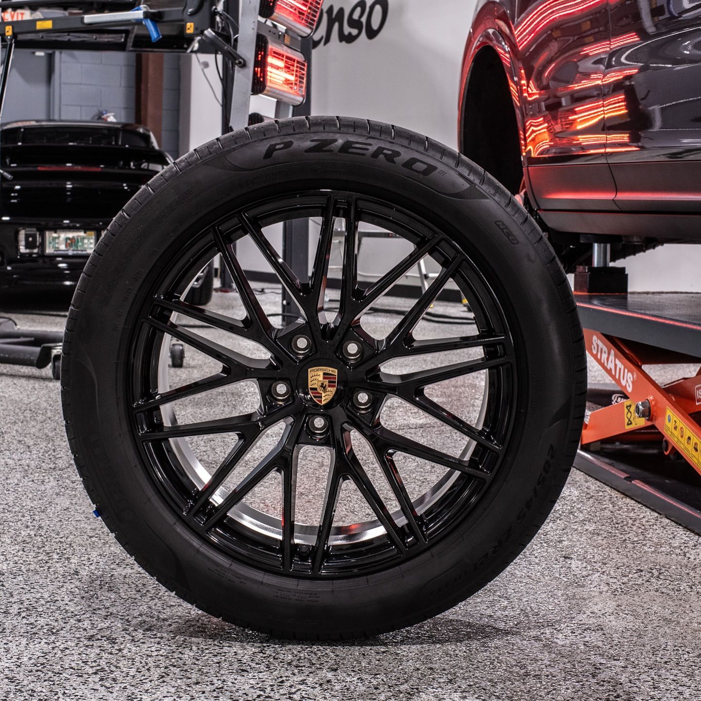 A car is sitting on a lift with a tire on it.