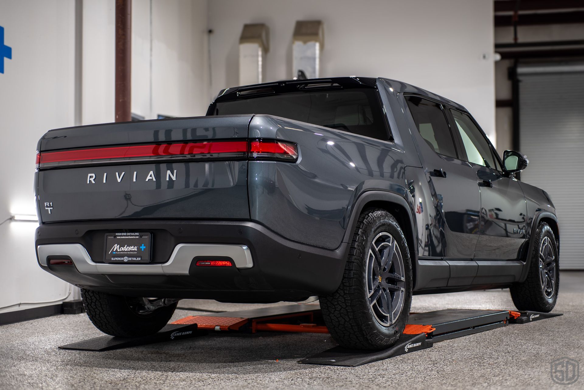 The rear end of a rivian truck is shown in a garage.