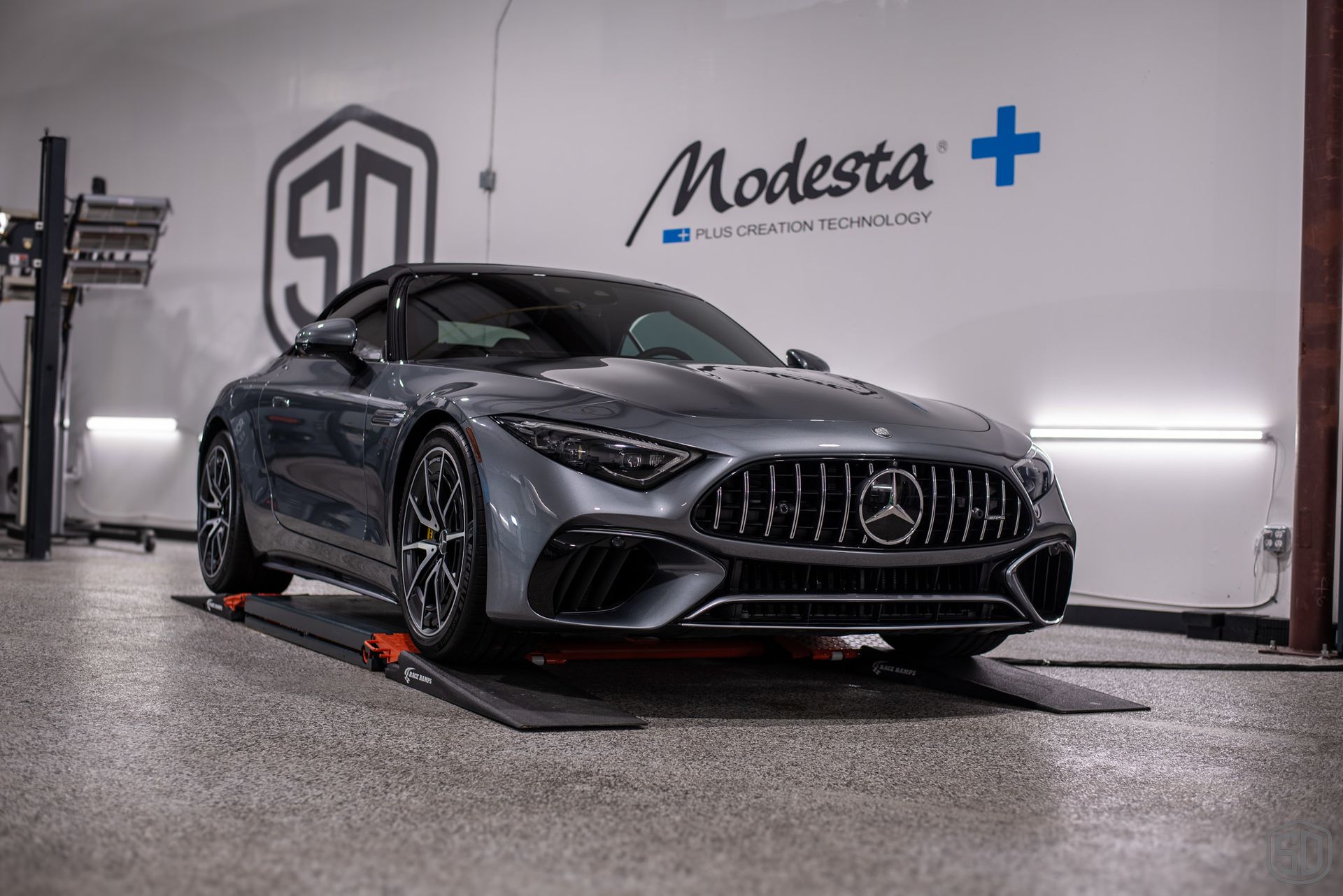 A mercedes benz sl63 amg is parked on a lift in a garage.