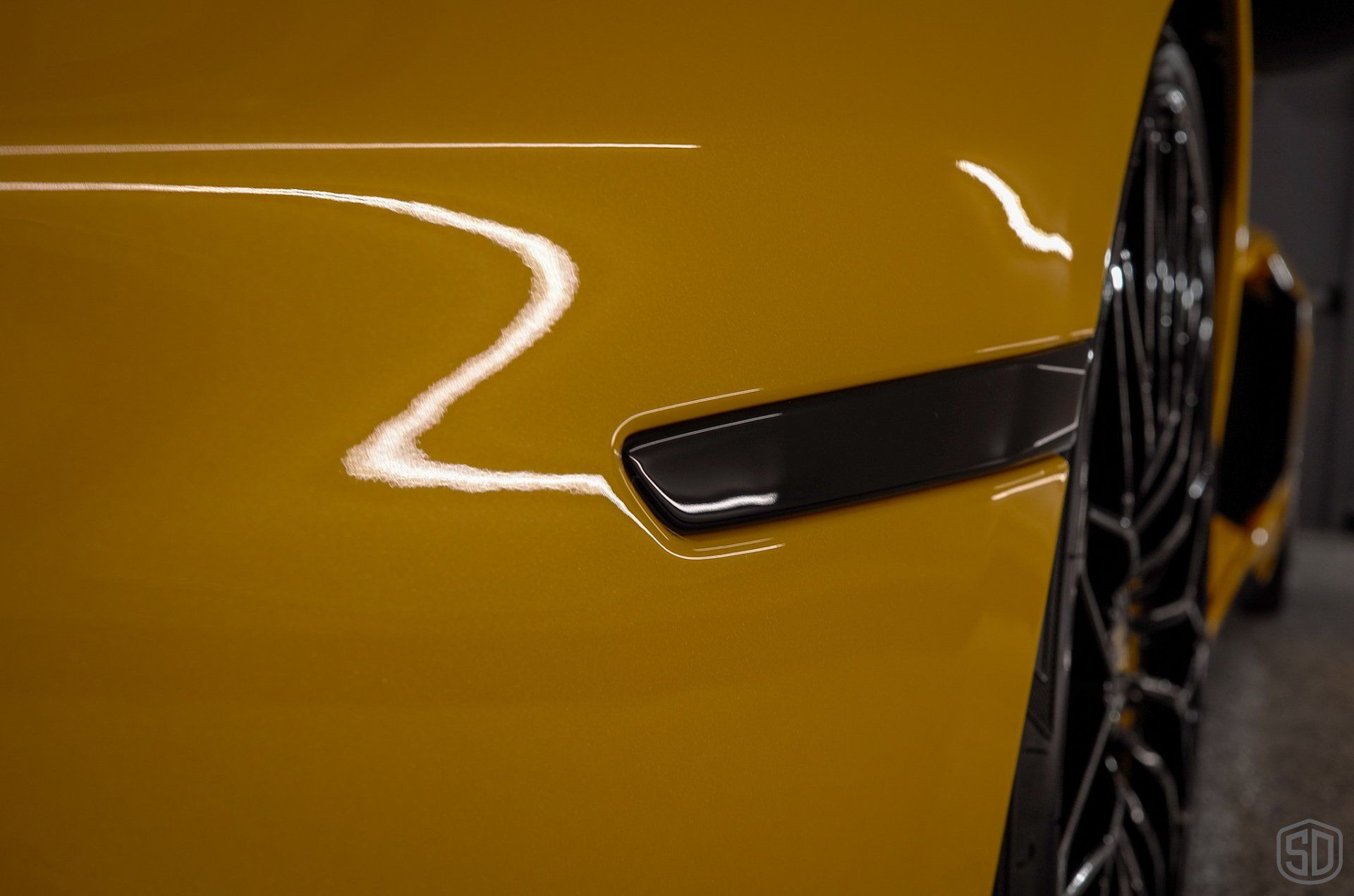 A close up of the side of a yellow sports car.