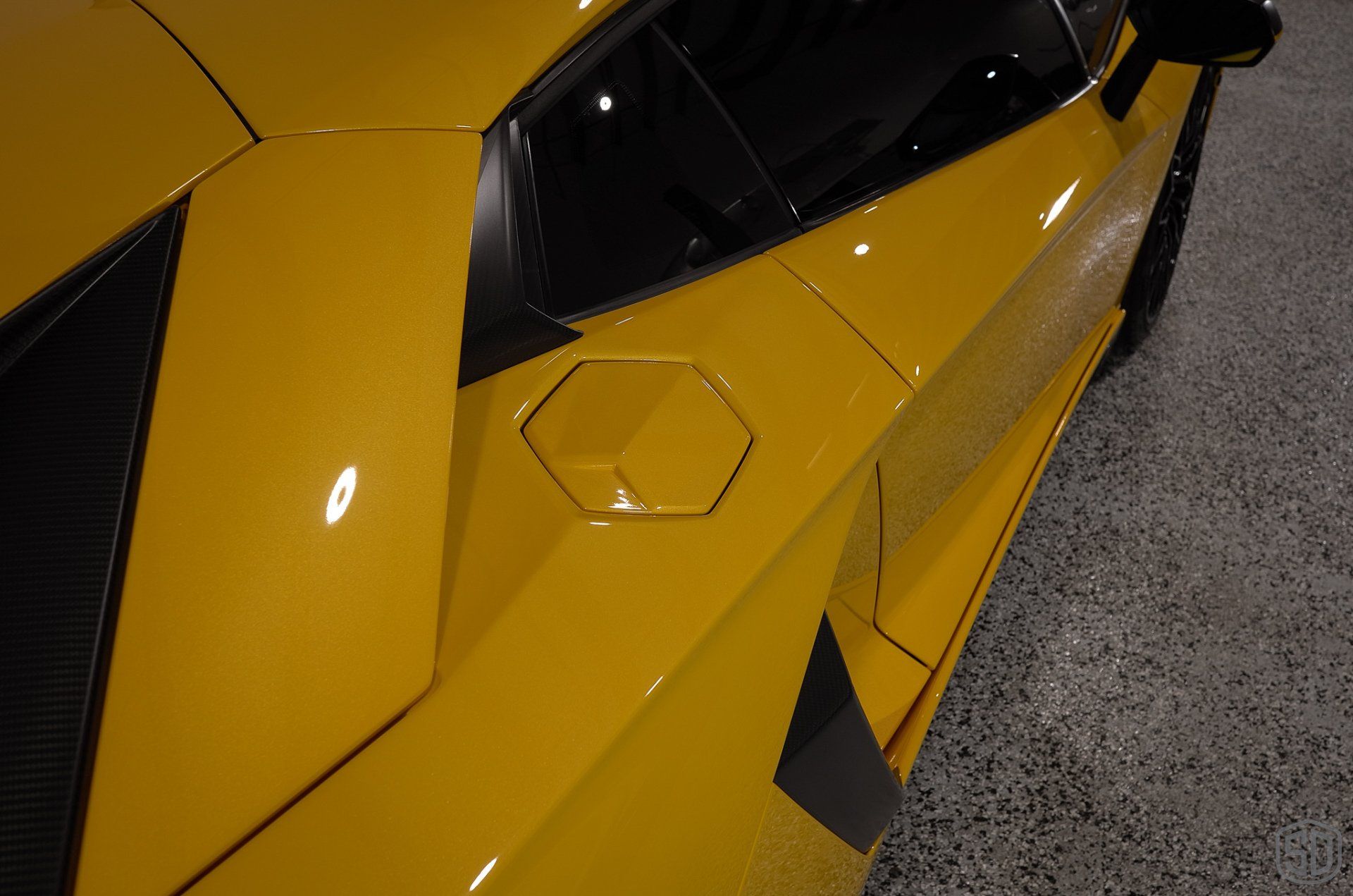 A yellow lamborghini aventador is parked in a garage.