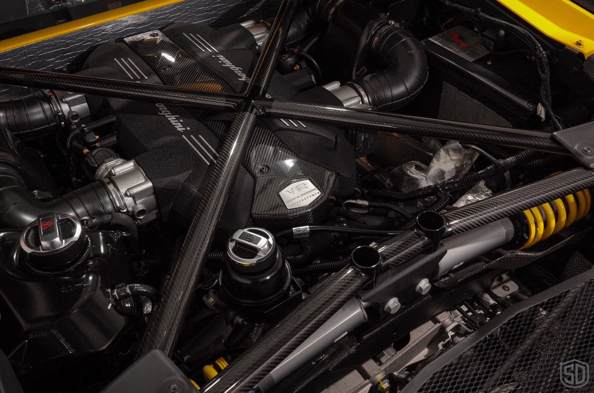 A close up of the engine of a yellow sports car.