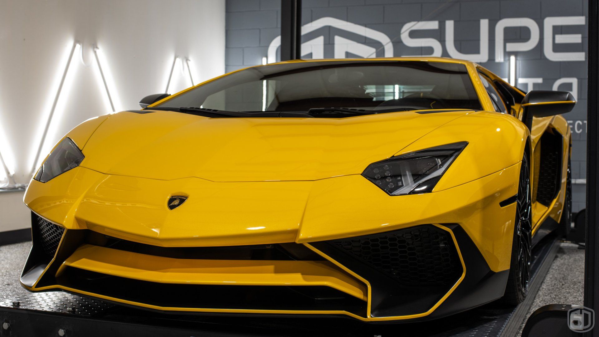 A yellow lamborghini aventador is parked in a garage.