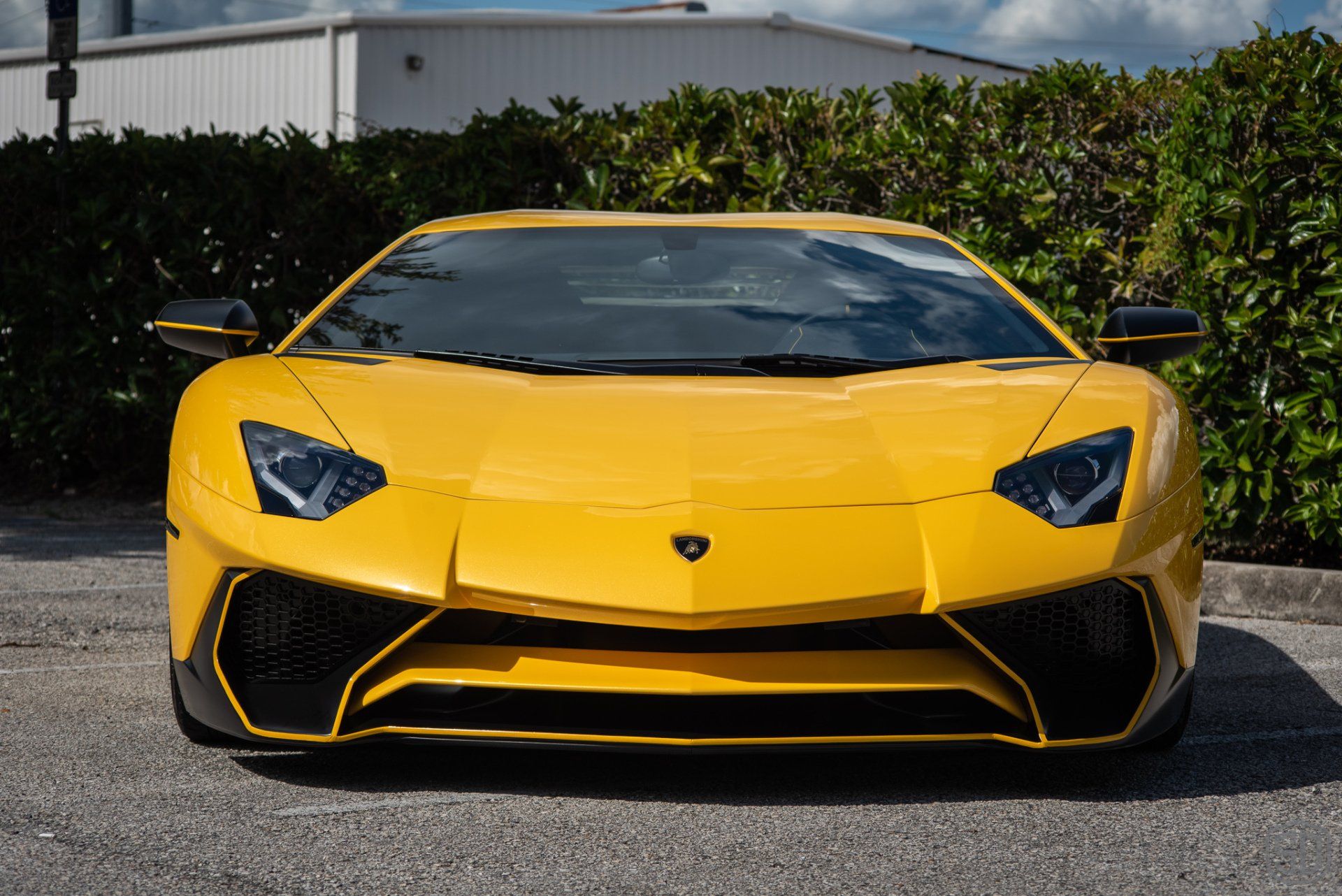 A yellow lamborghini aventador is parked in a parking lot.