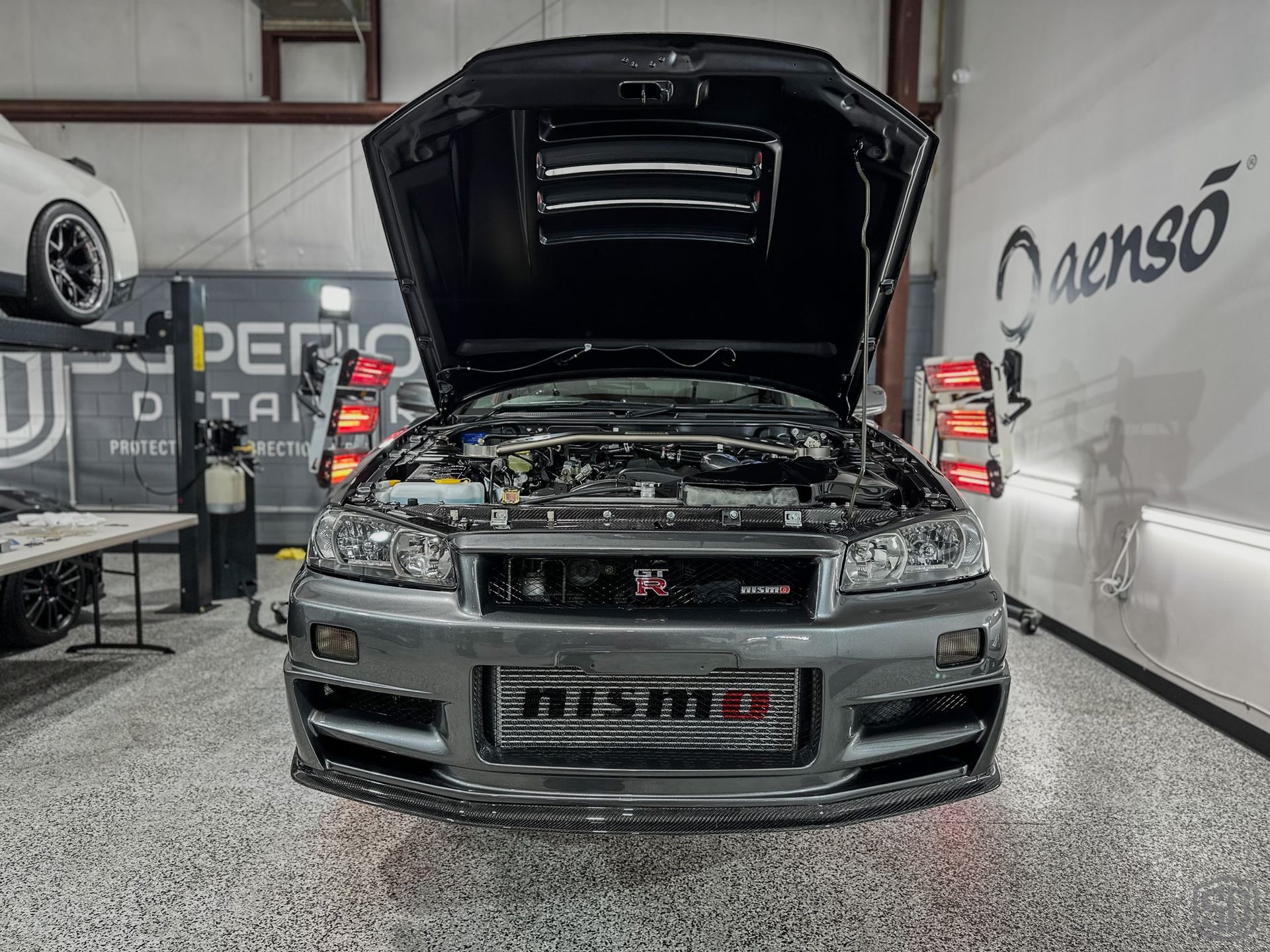 A car with the hood up is parked in a garage.
