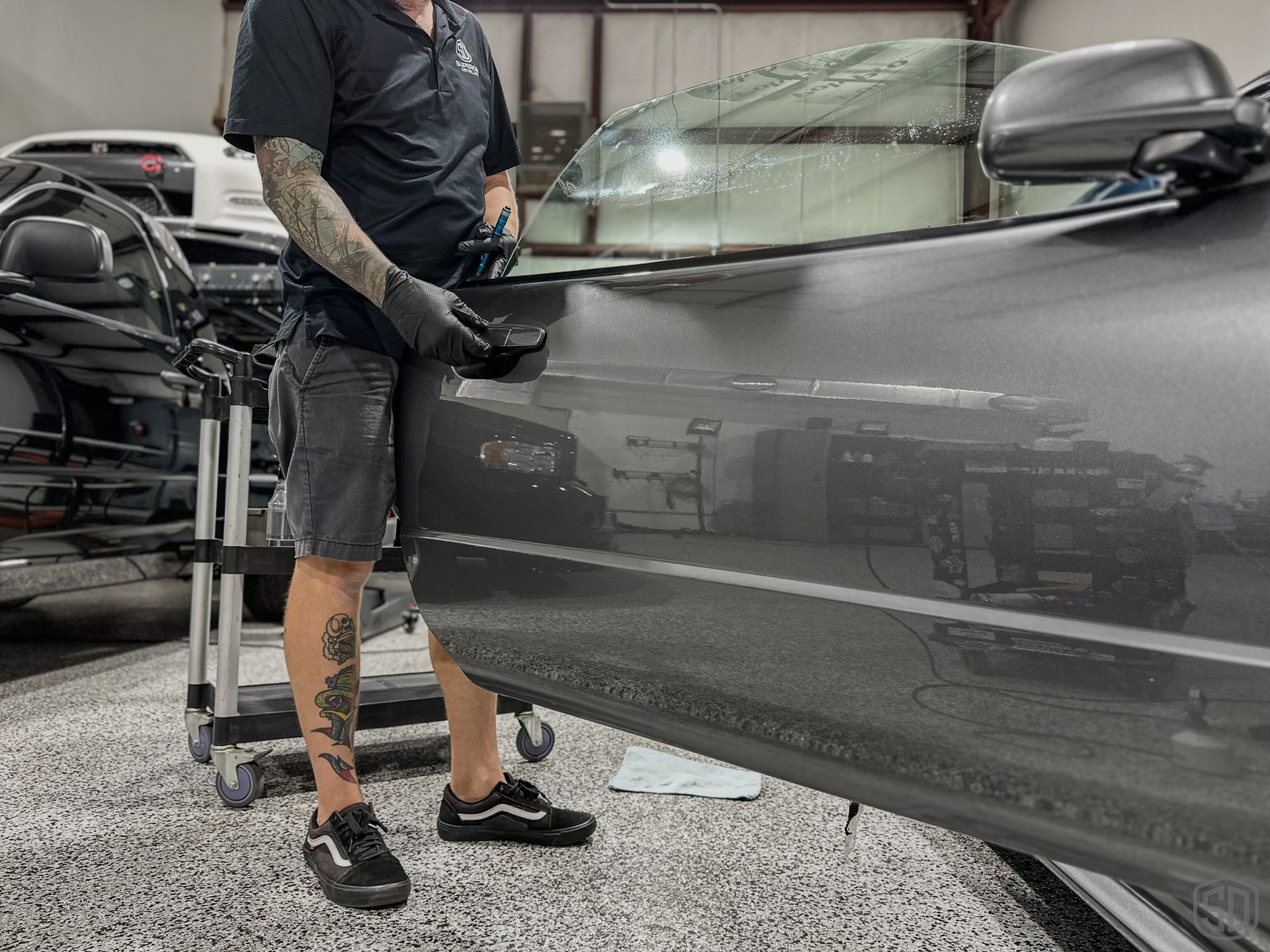 A man is standing next to a car in a garage.