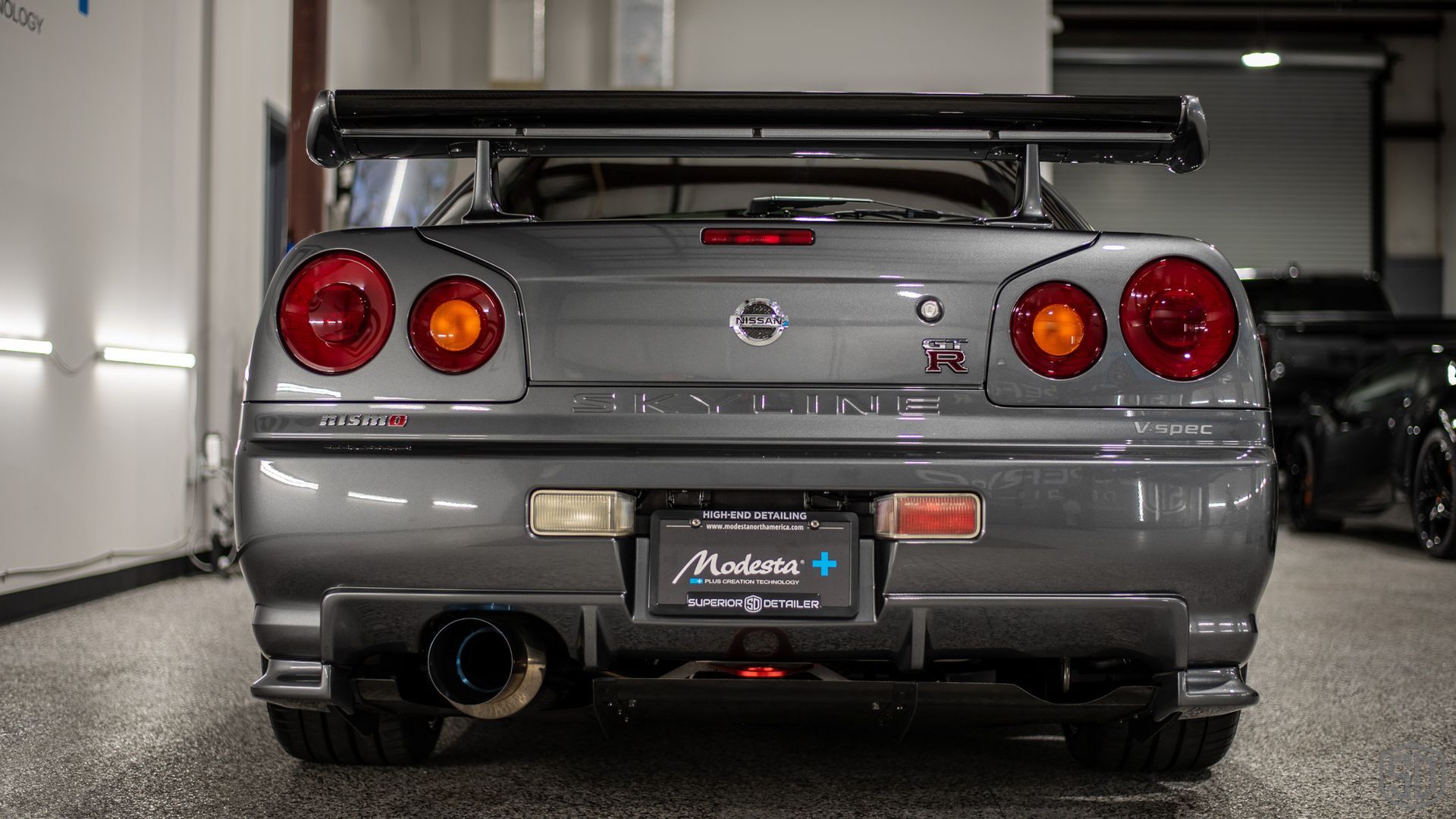 The rear end of a nissan skyline r34 is shown in a garage.