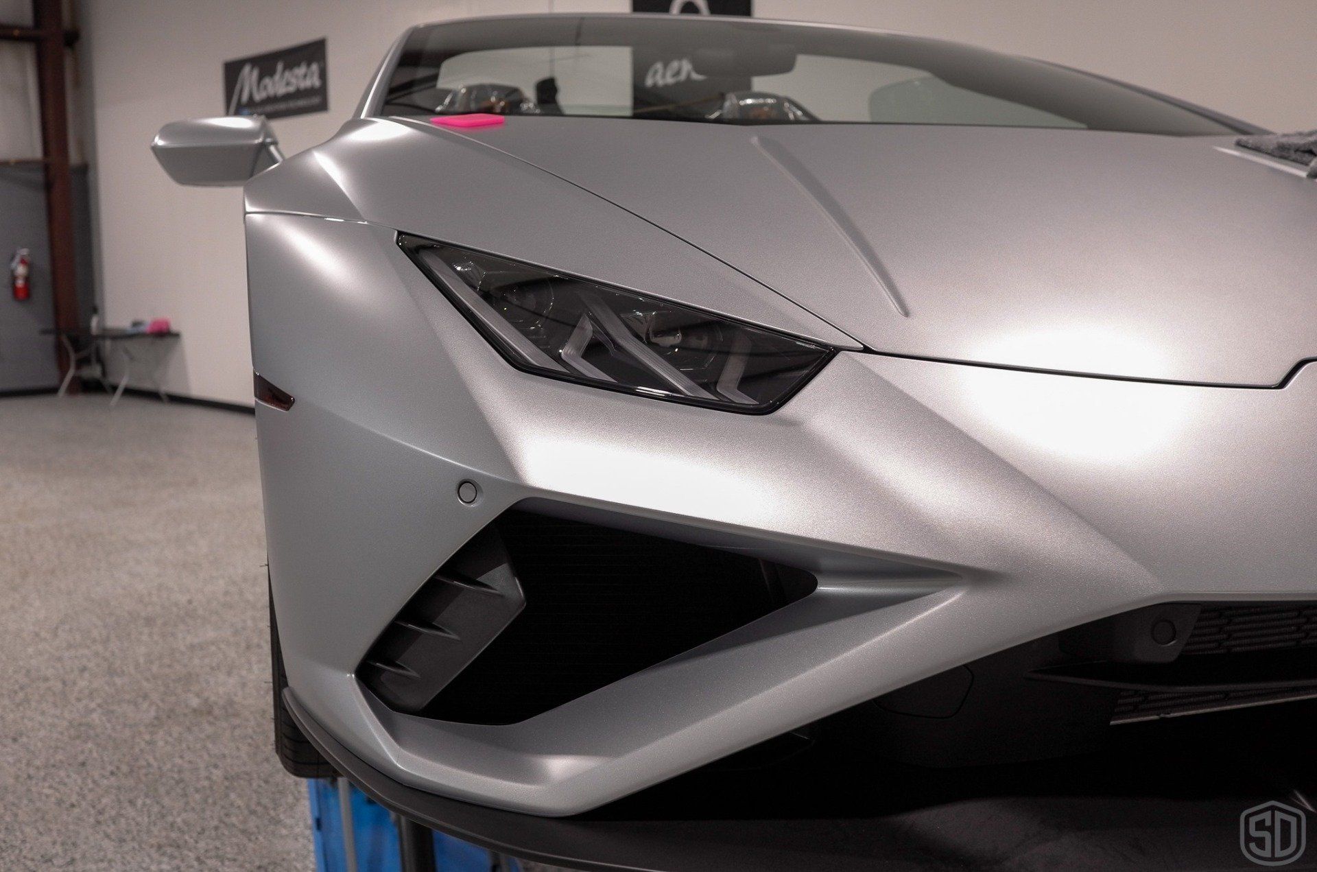 A silver lamborghini huracan is parked in a garage.
