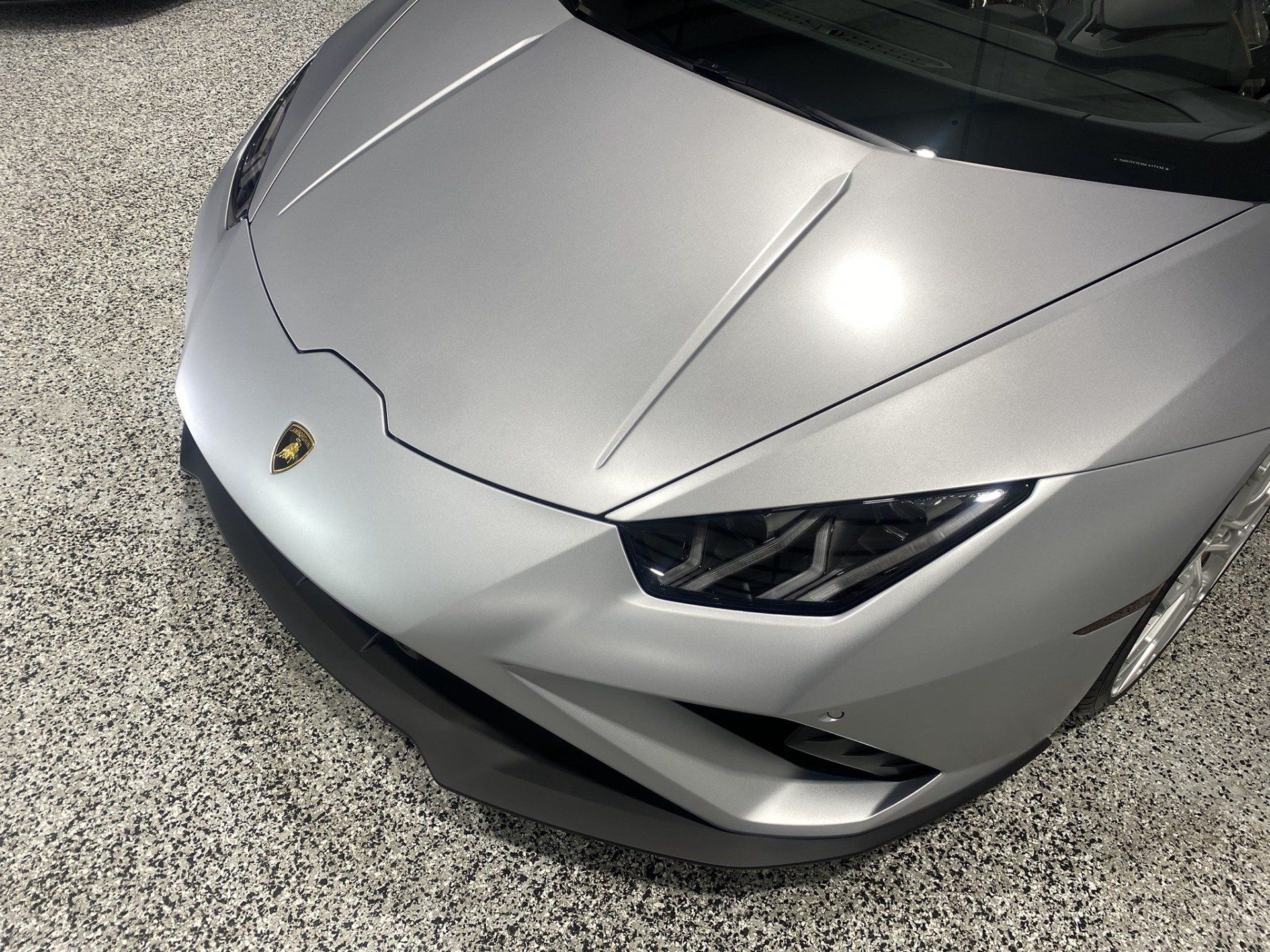 A silver lamborghini huracan is parked in a garage.