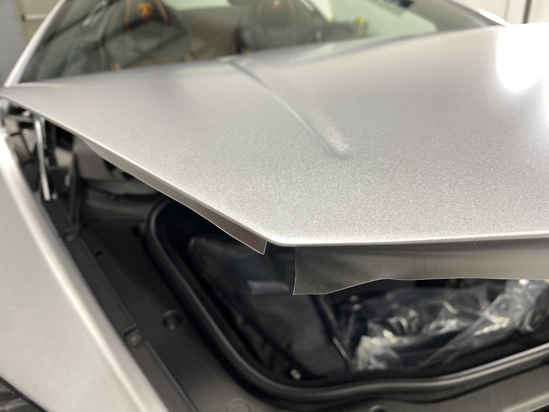 A silver car with the hood open and the trunk open