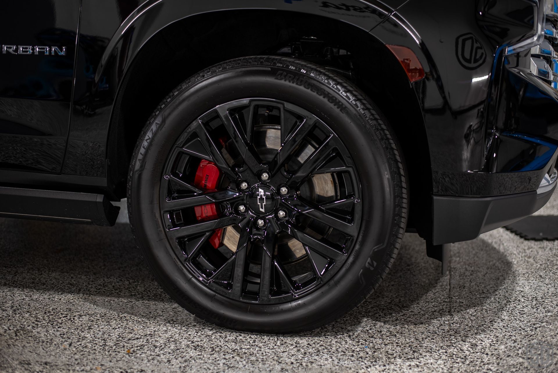 A black suv with red brake calipers is parked in a garage.