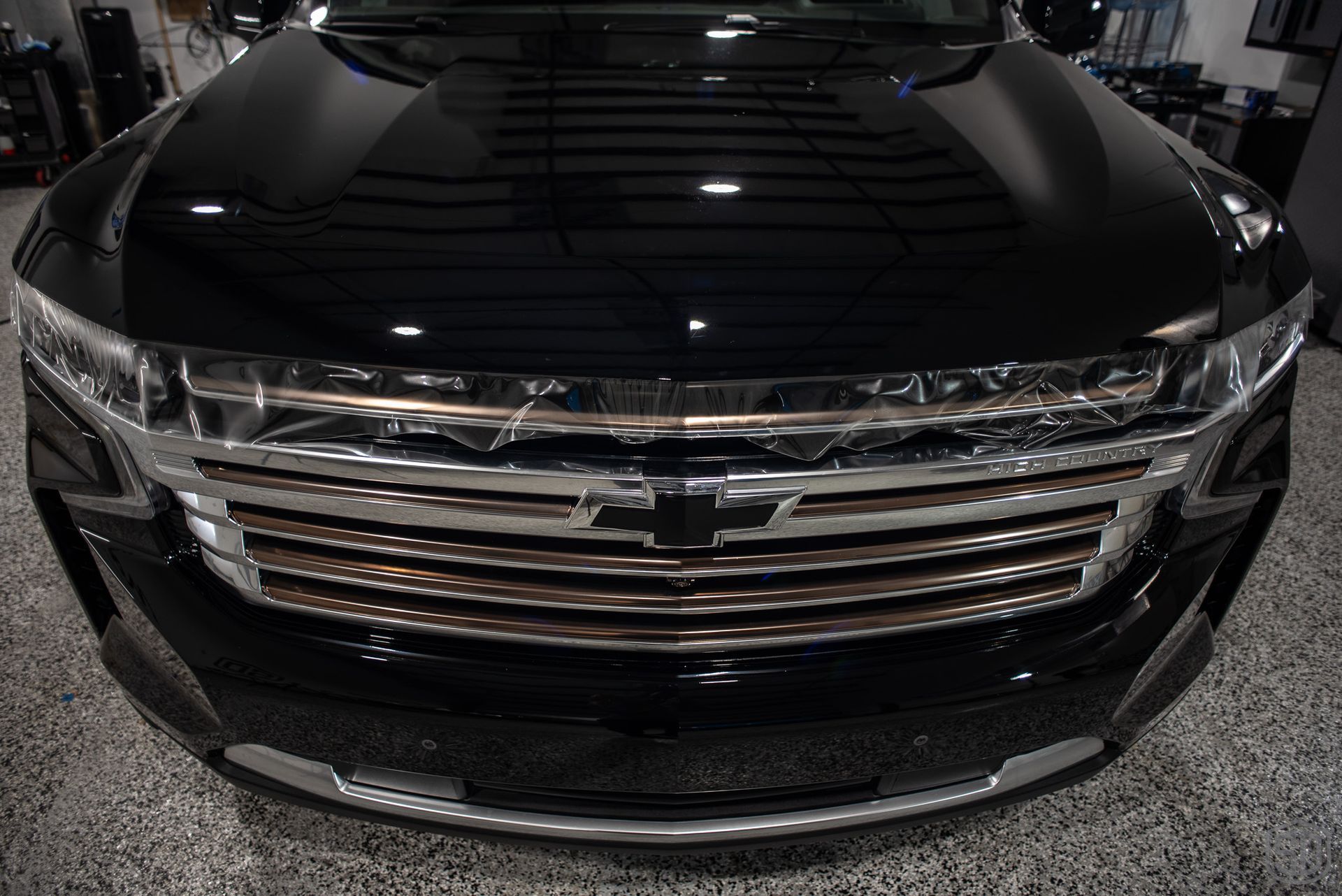 A black car with a chrome grille is parked in a garage.