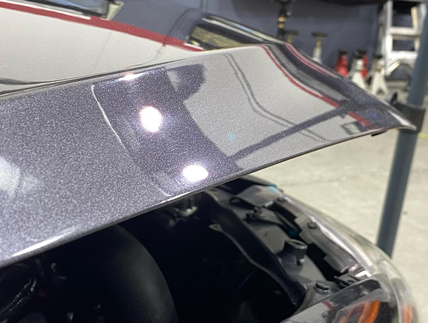 The hood of a car is open in a garage.