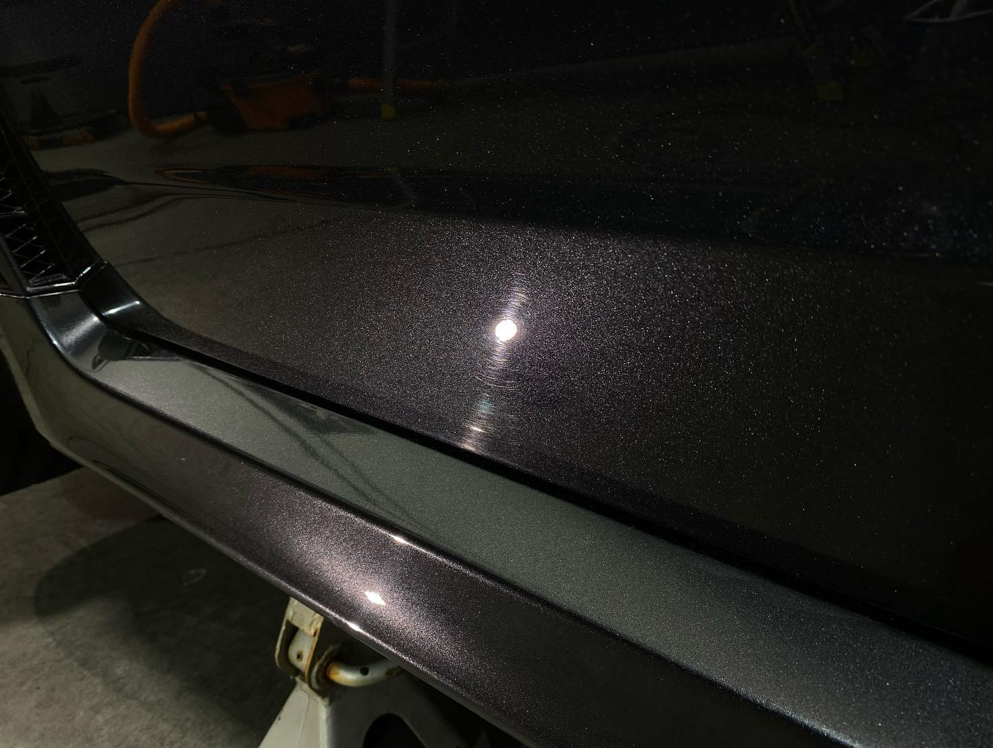 A close up of a black car 's hood and bumper.