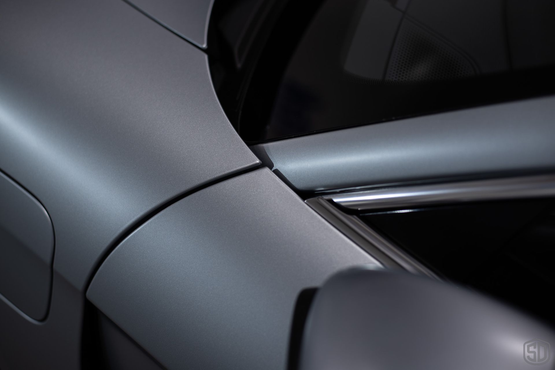 A close up of the side of a gray car that has a matte finish