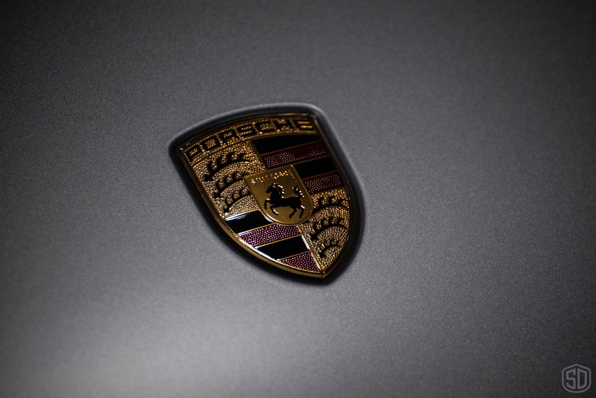 A close up of a porsche logo on a gray surface.