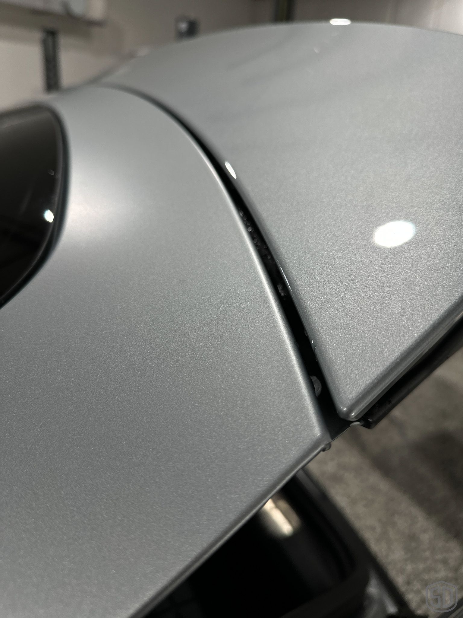 A close up of a car 's hood in a garage that has a glossy finish