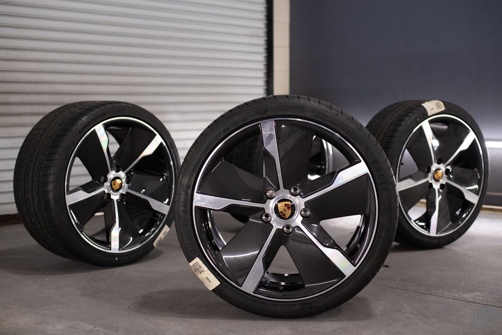 Wheels have been removed from the Taycan and are sitting on the ground.