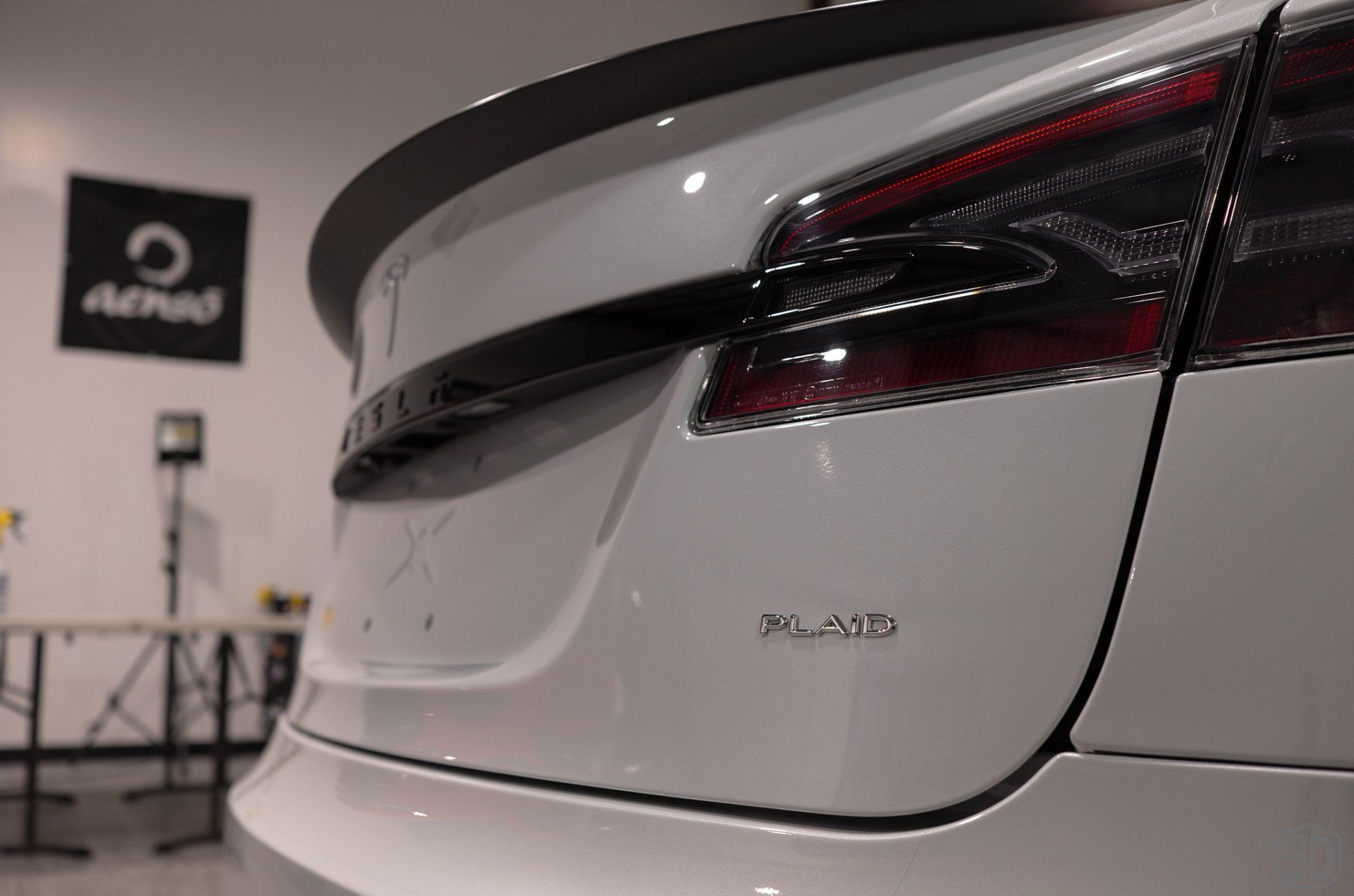 A white tesla model s is parked in a garage.